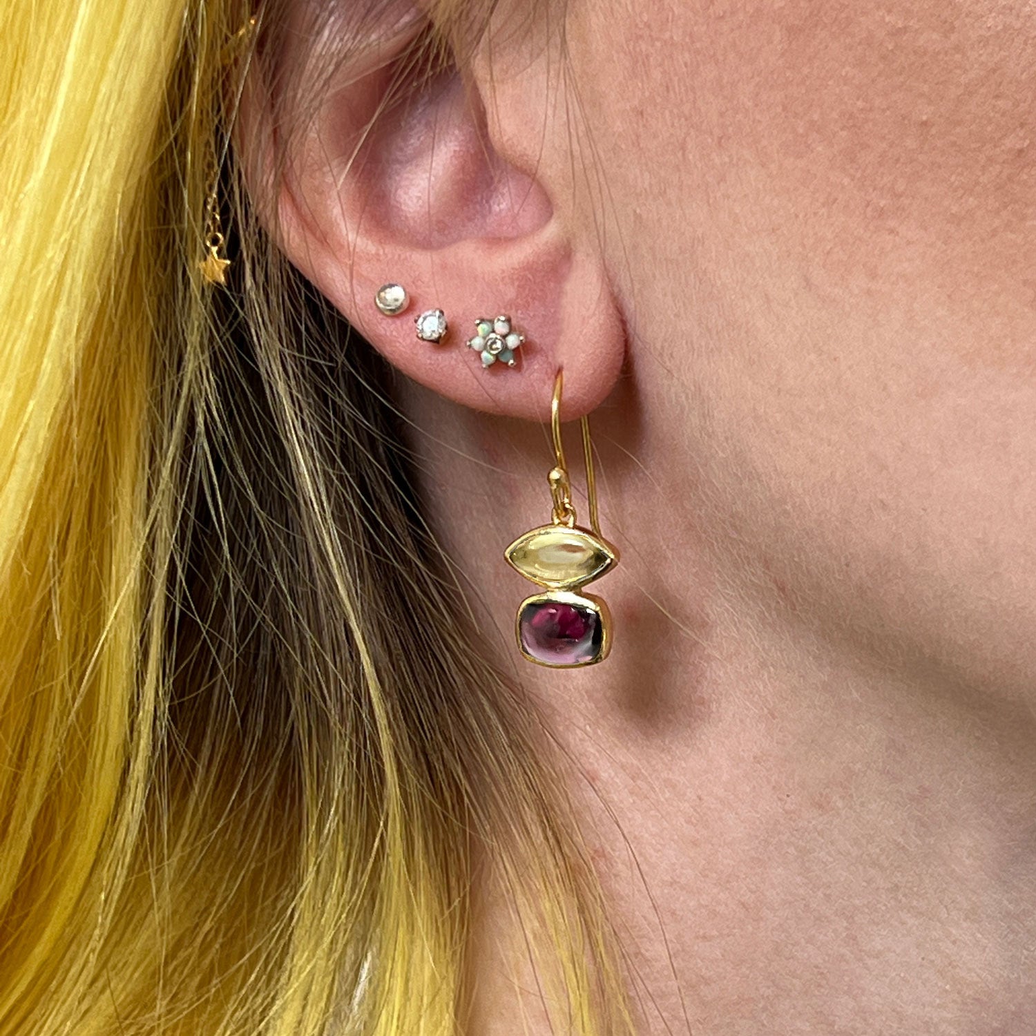 A Fairtrade Beryl Lemon Quartz & Garnet Vermeil Earring in an ear.