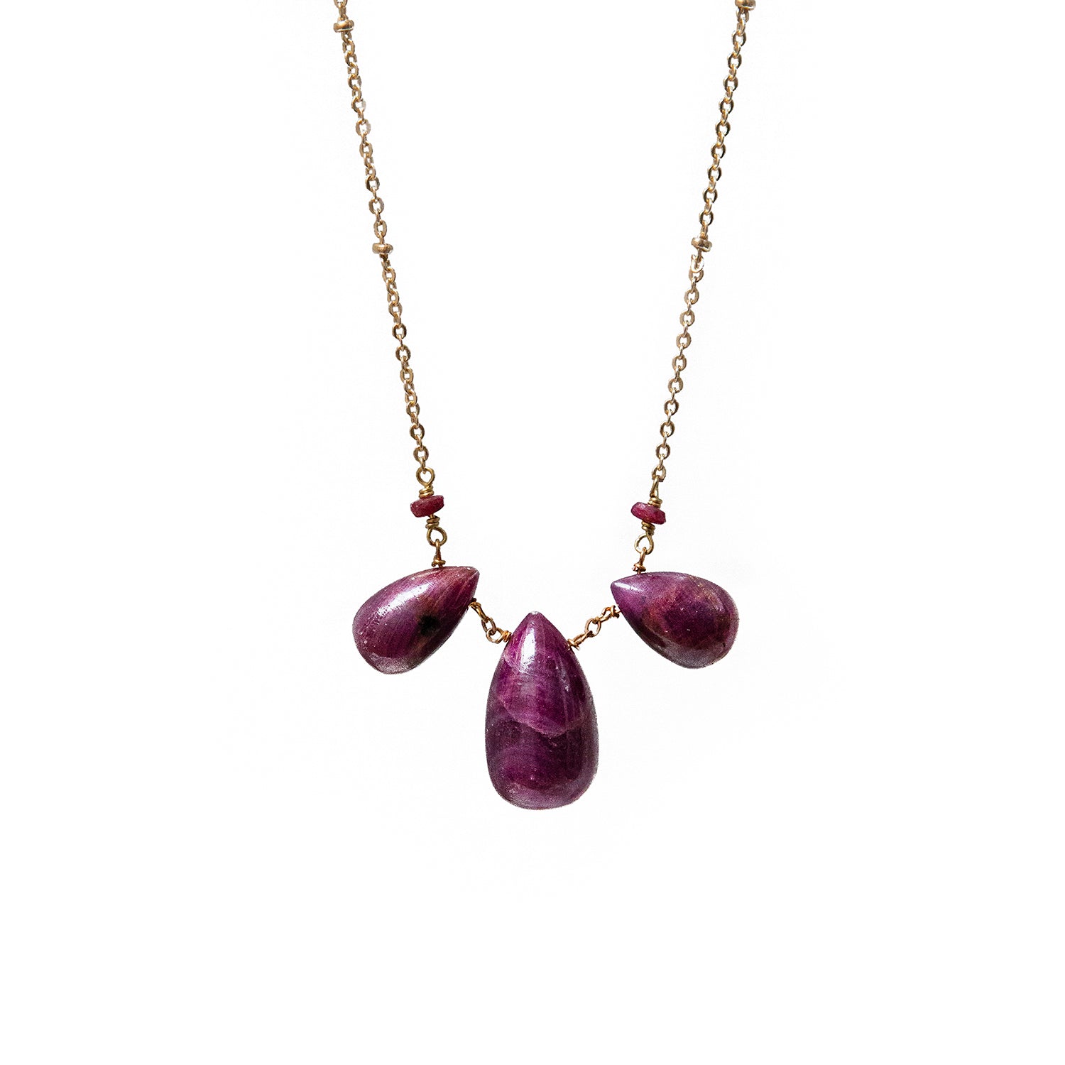 Necklace with three teardrop-shaped rubies on a gold chain against a white background
