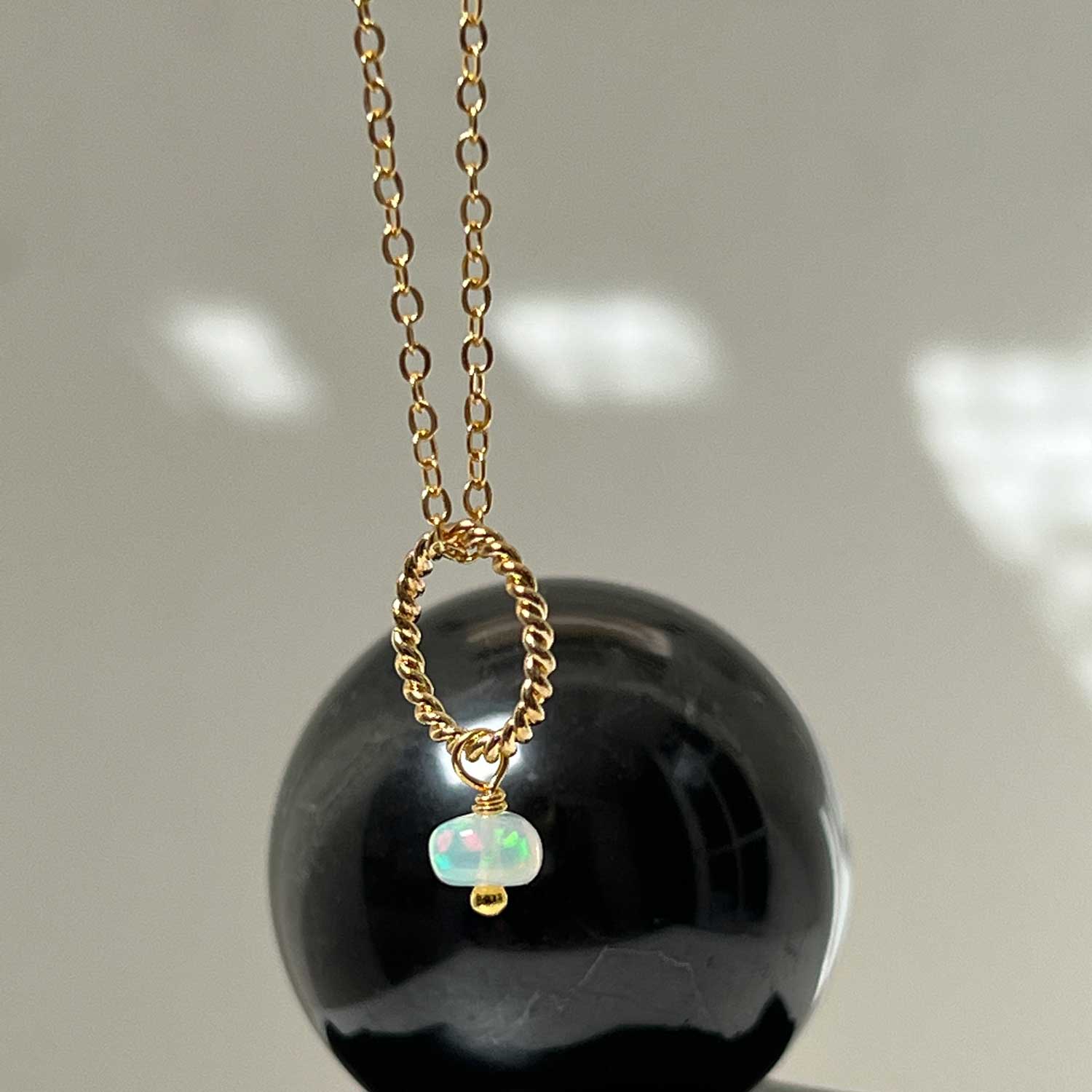 Gold-plated opal pendant necklace against a round stone