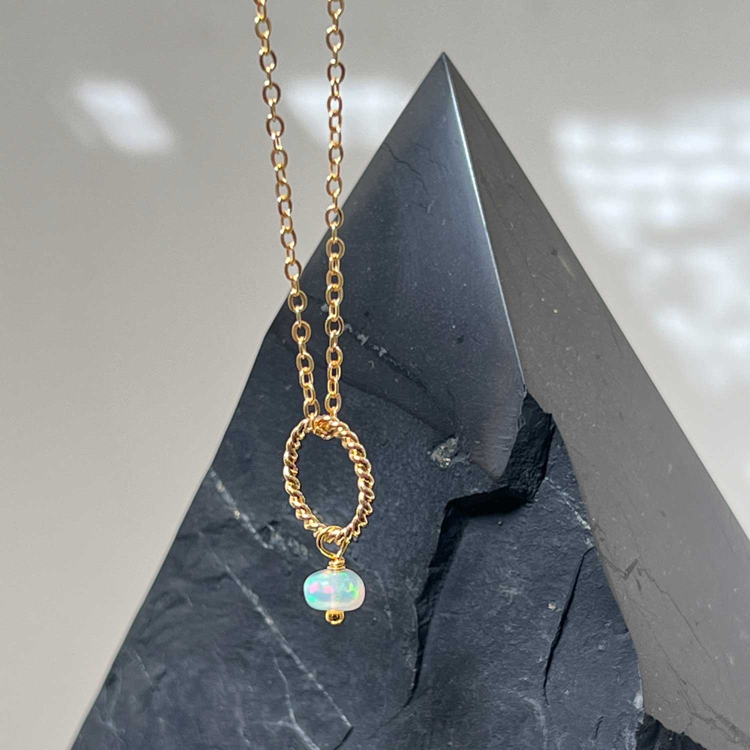 Gold-plated opal pendant necklace against a dark crystal