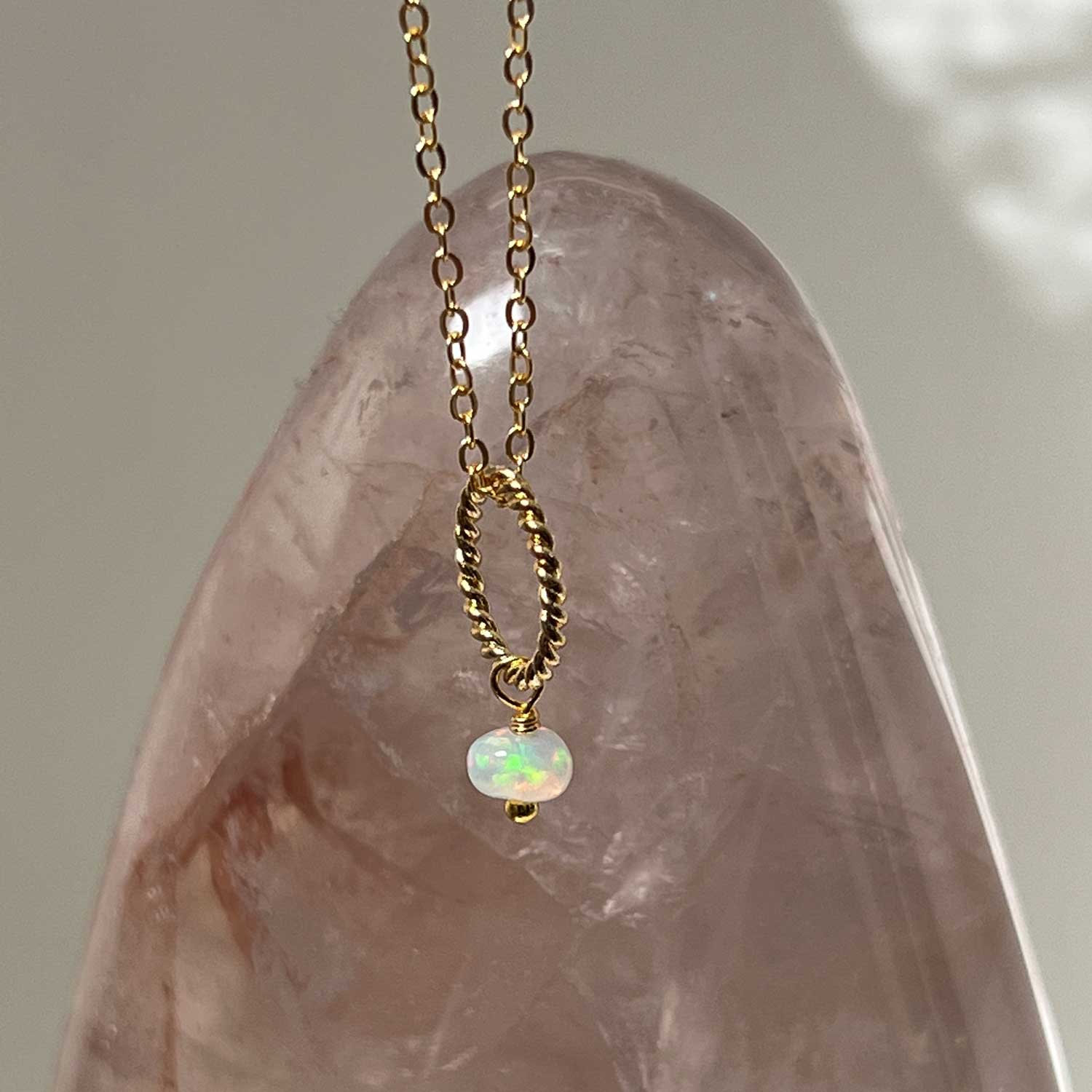 Gold-plated opal pendant necklace against a crystal background
