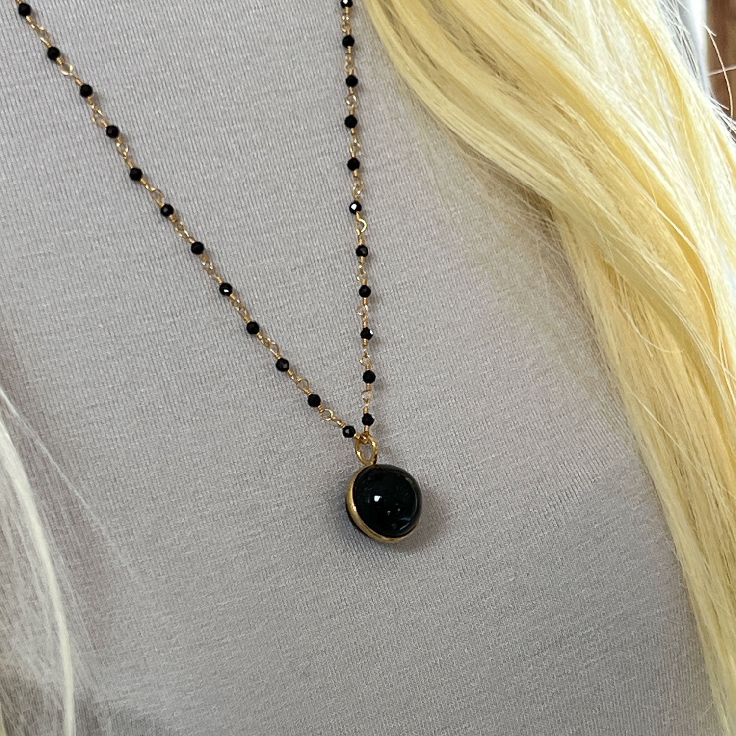 black onyx rosary necklace with a black onyx pendant displayed on a model wearing a grey sweater