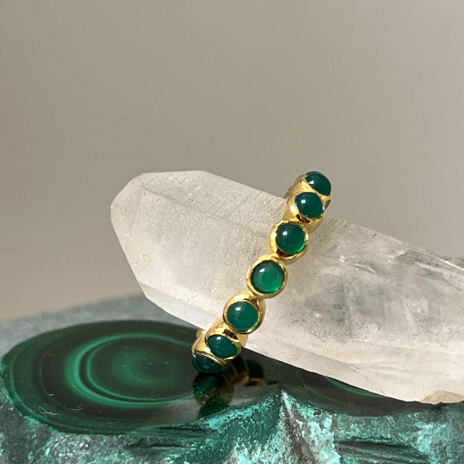 A gold-plated ring with green onyx cabochons and vermeil detailing on a background of crystals