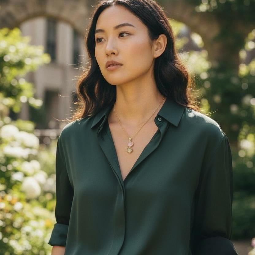 Woman wearing a rose quartz and prehnite necklace with a green shirt with a blurred garden background