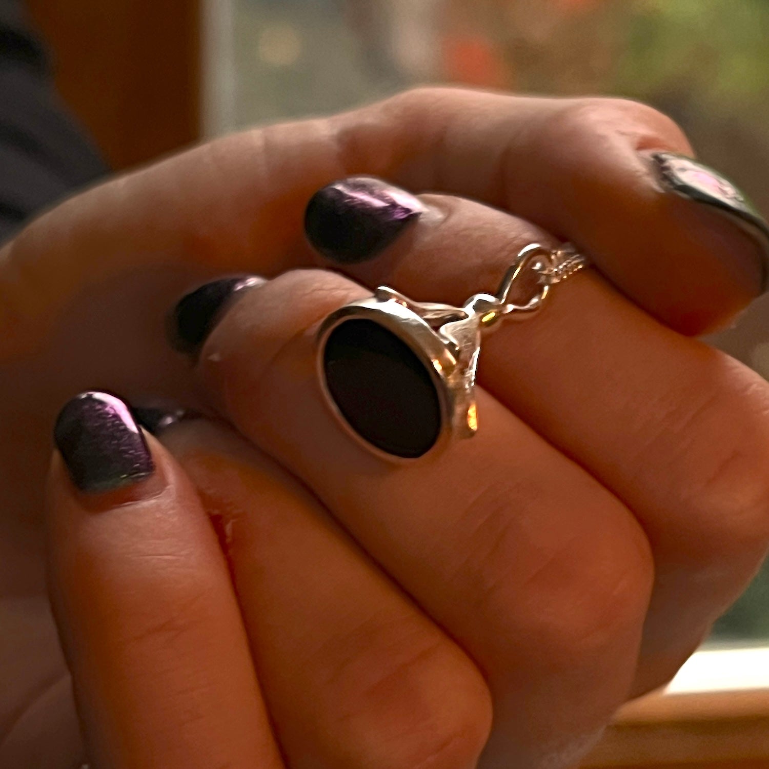 Close-up of a hand carrying a black onyx stamp pendant.