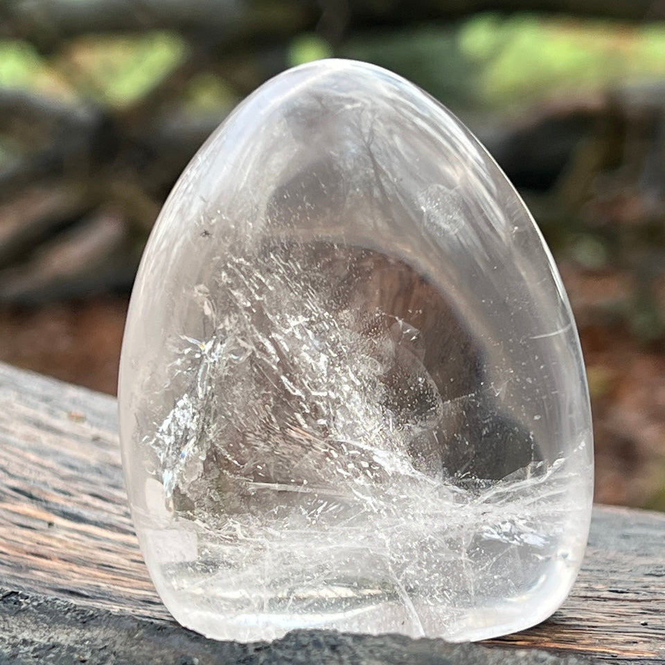 Clear polished crystal rock on a wooden surface with blurred natural background