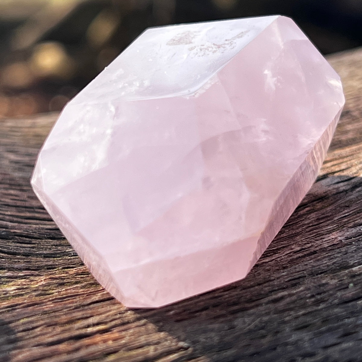 Close up of a Rose quartz crystal point on a wooden bench