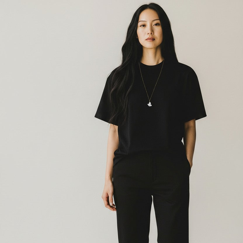 Person wearing a black t-shirt and a white agate dove necklace with a gold chain