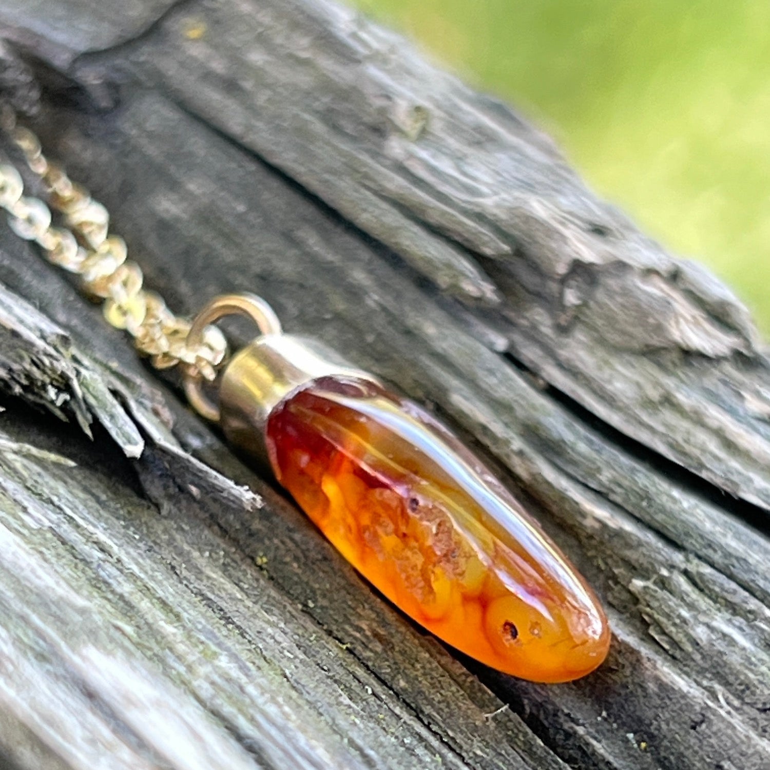 Carnelian necklace with a gold chain on a wooden surface