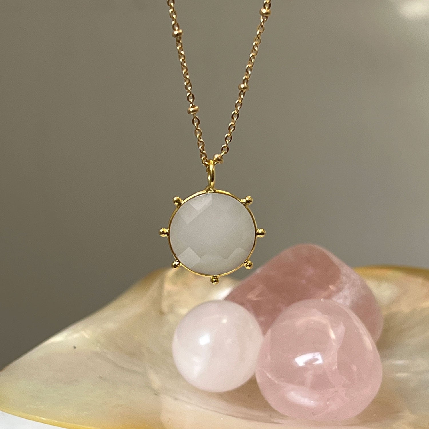 Astrid White Chalcedony Pendant with pink crystals in the background
