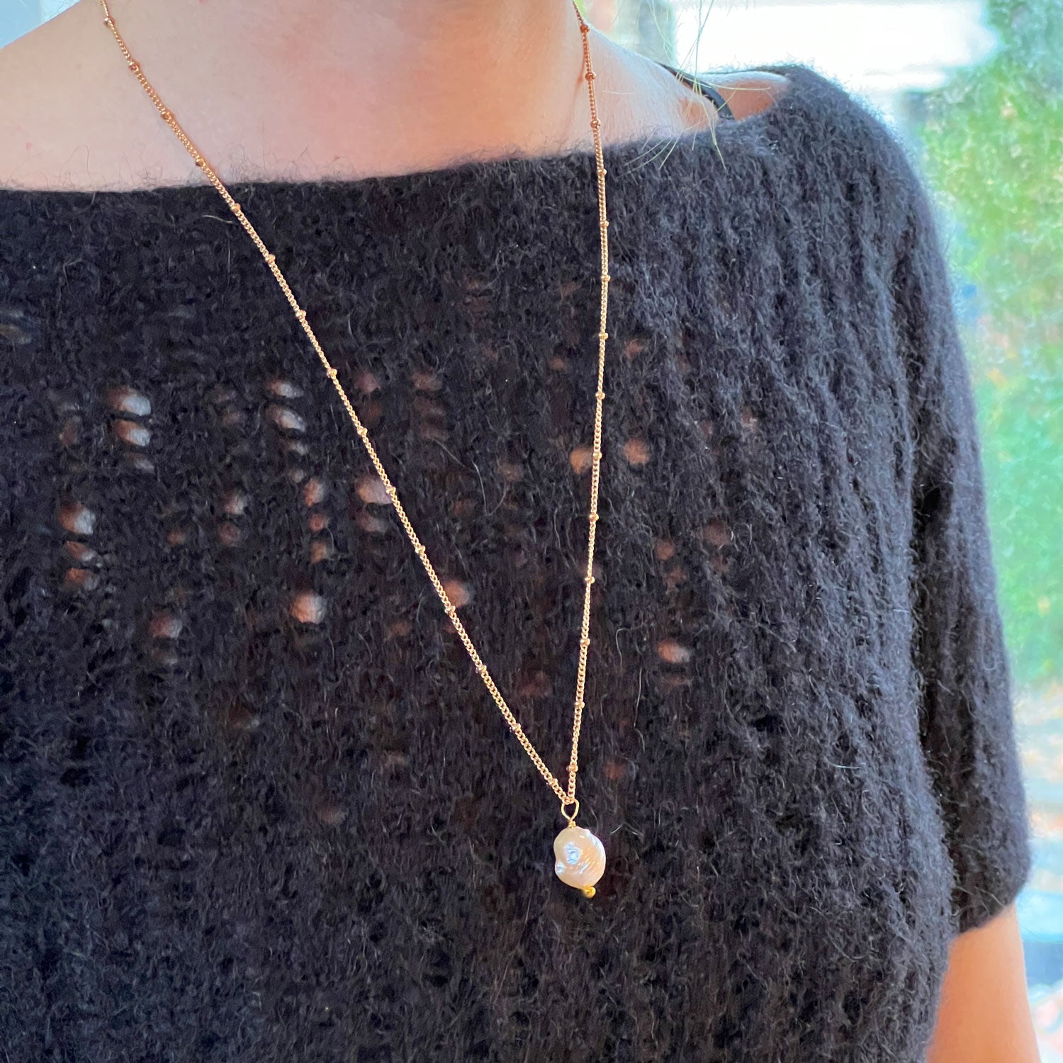 Large Baroque Pink Pearl Pendant worn by a model with a black top