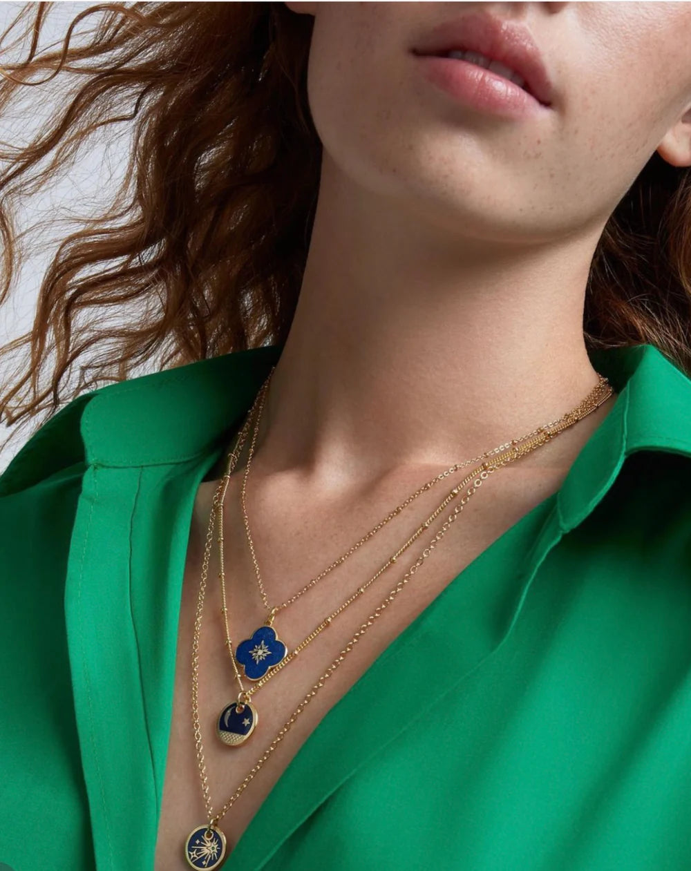 A model wearing 3 different gold-plated pendants