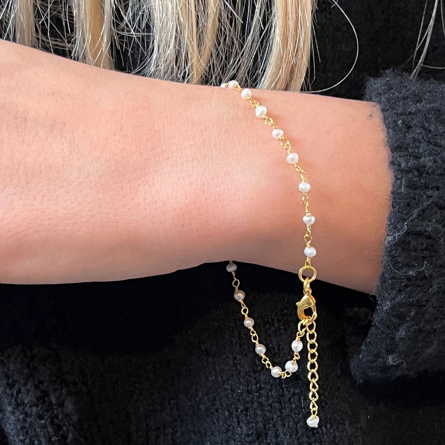 A model wearing a handmade freshwater pearl rosary gold-plated bracelet around her wrist