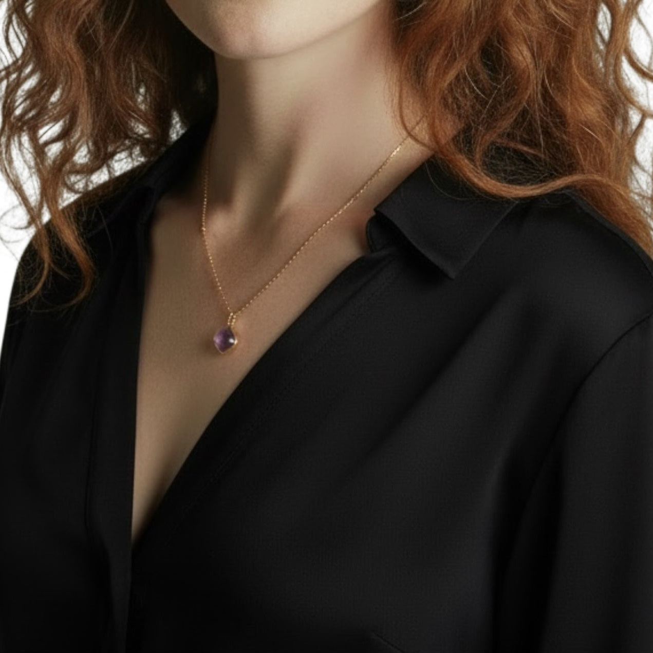 Necklace with a purple amethyst worn by a person in a black shirt.