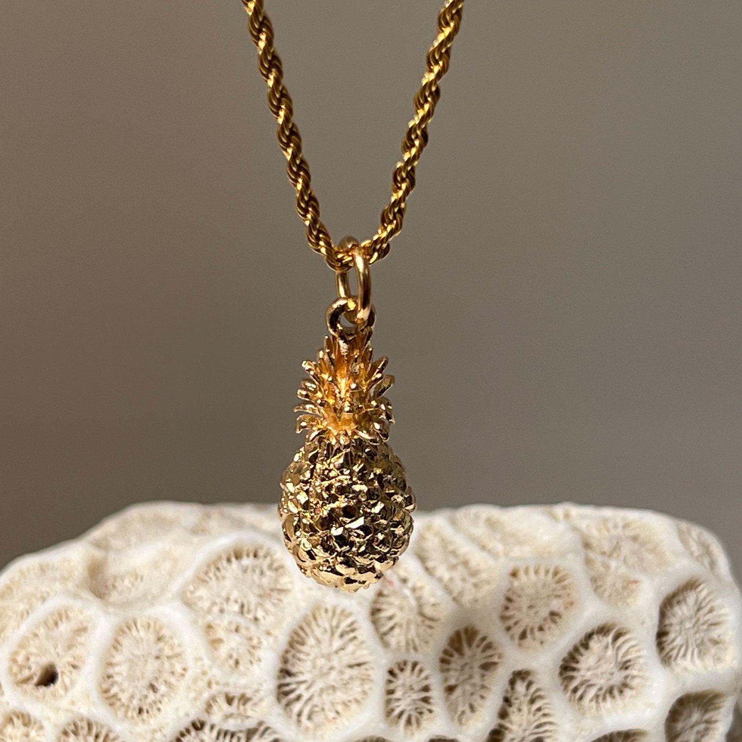 A close up of a Pineapple Charm Pendant on a chain