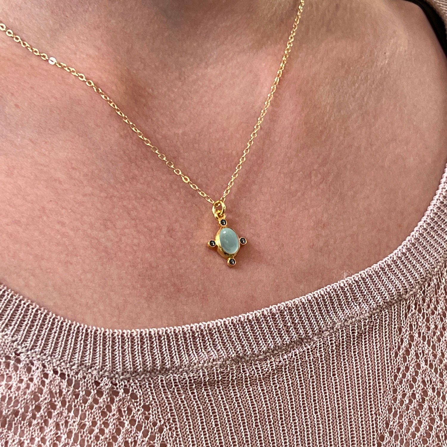 Aqua Chalcedony & Sapphire Zircon Pendant on a gold plated chain worn around the neck of someone wearing a beige top