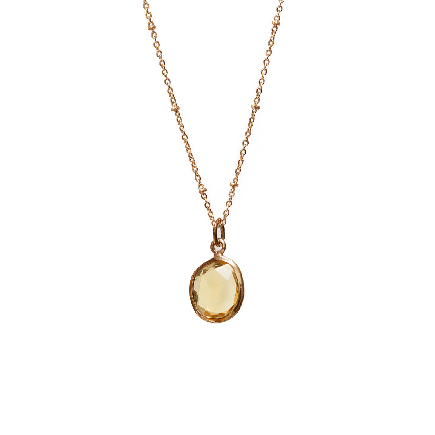 Gold necklace with a yellow freeform citrine gemstone pendant on a white background