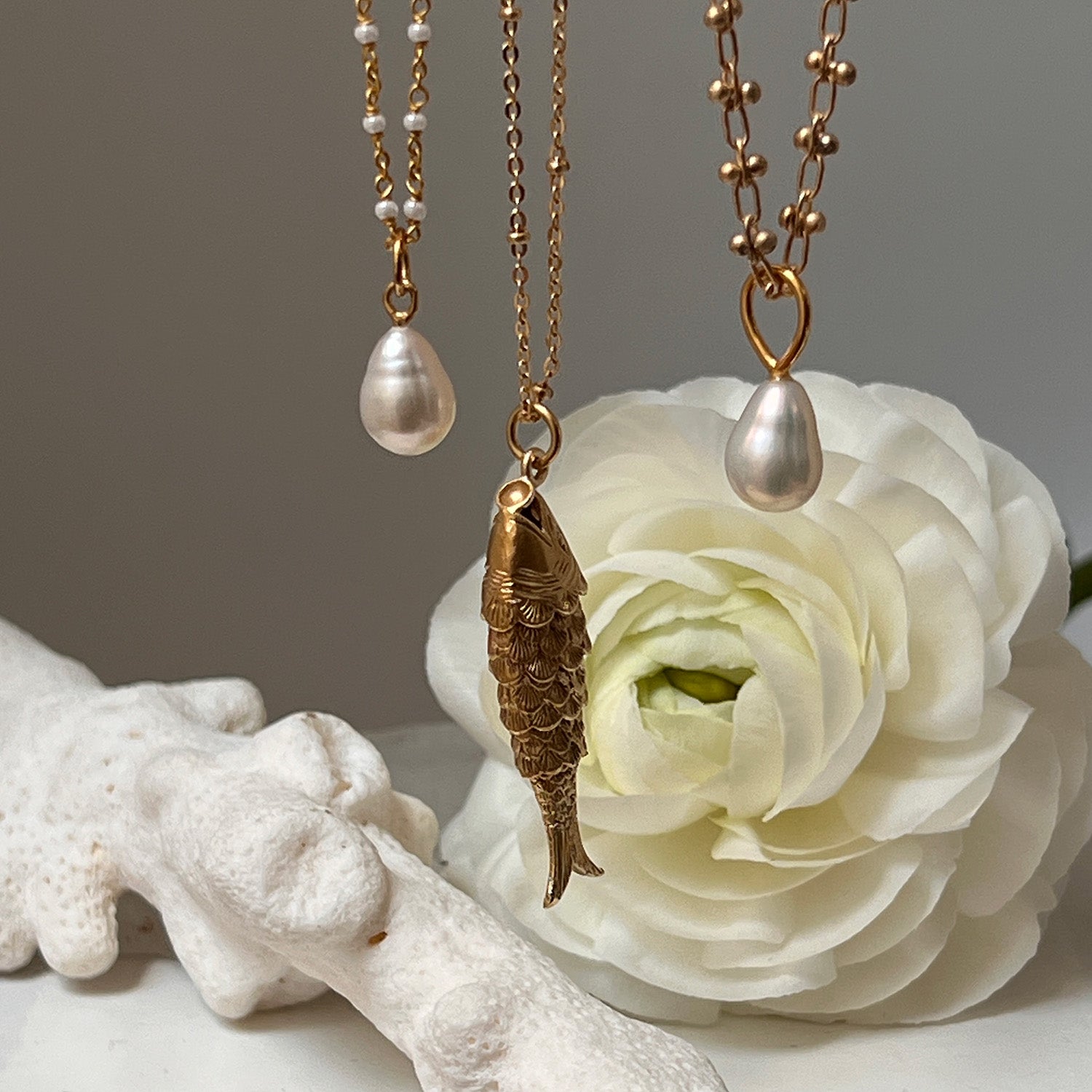 Three necklaces including Freshwater pearl pendant necklace displayed with a rose