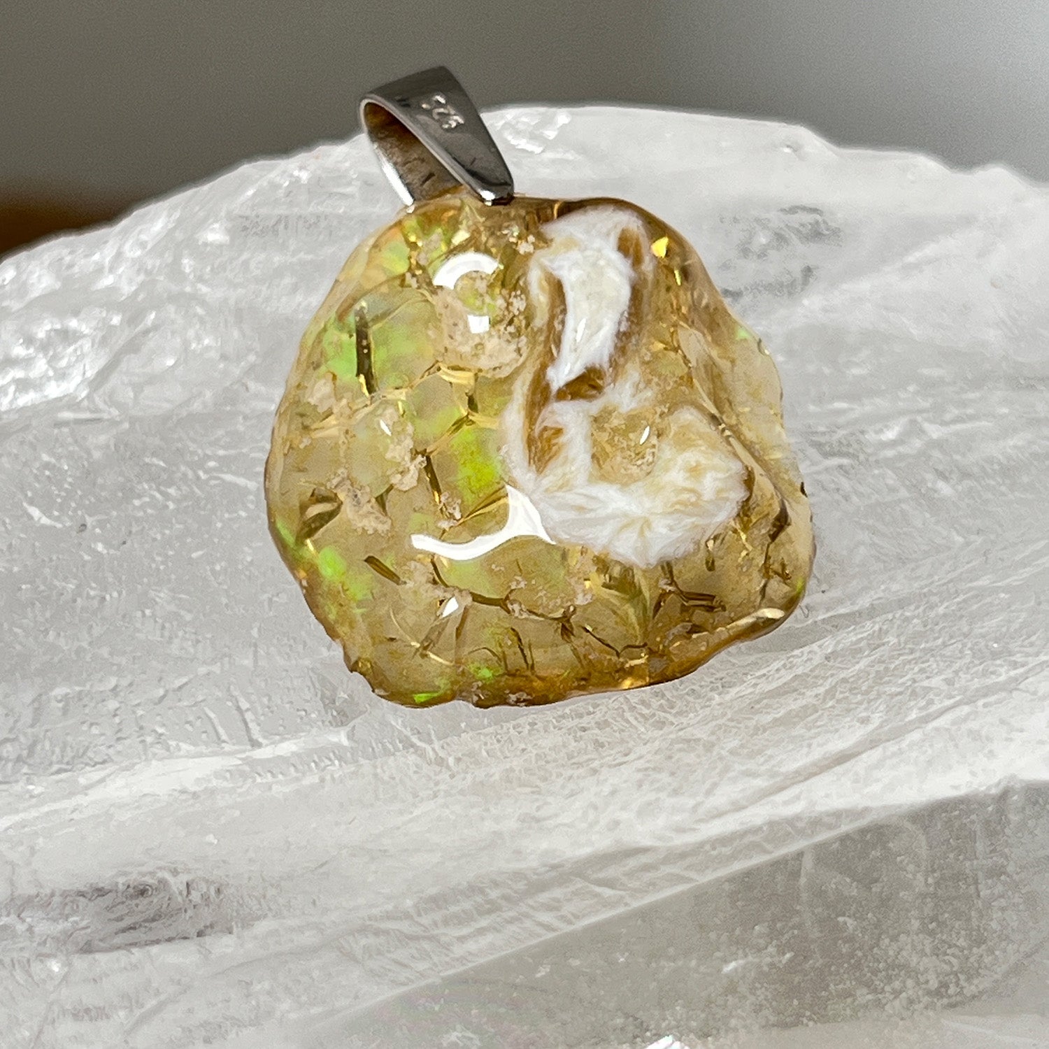 Ethiopian fire opal pendant on a white stone background