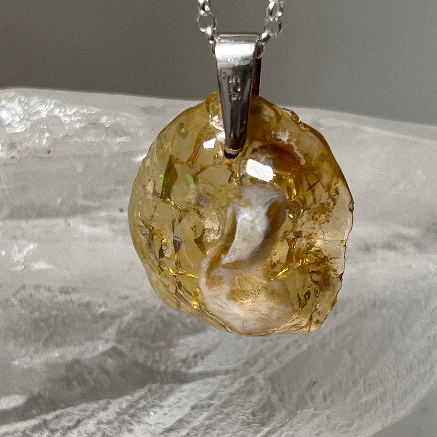 Ethiopian fire opal pendant on a chain against a neutral background