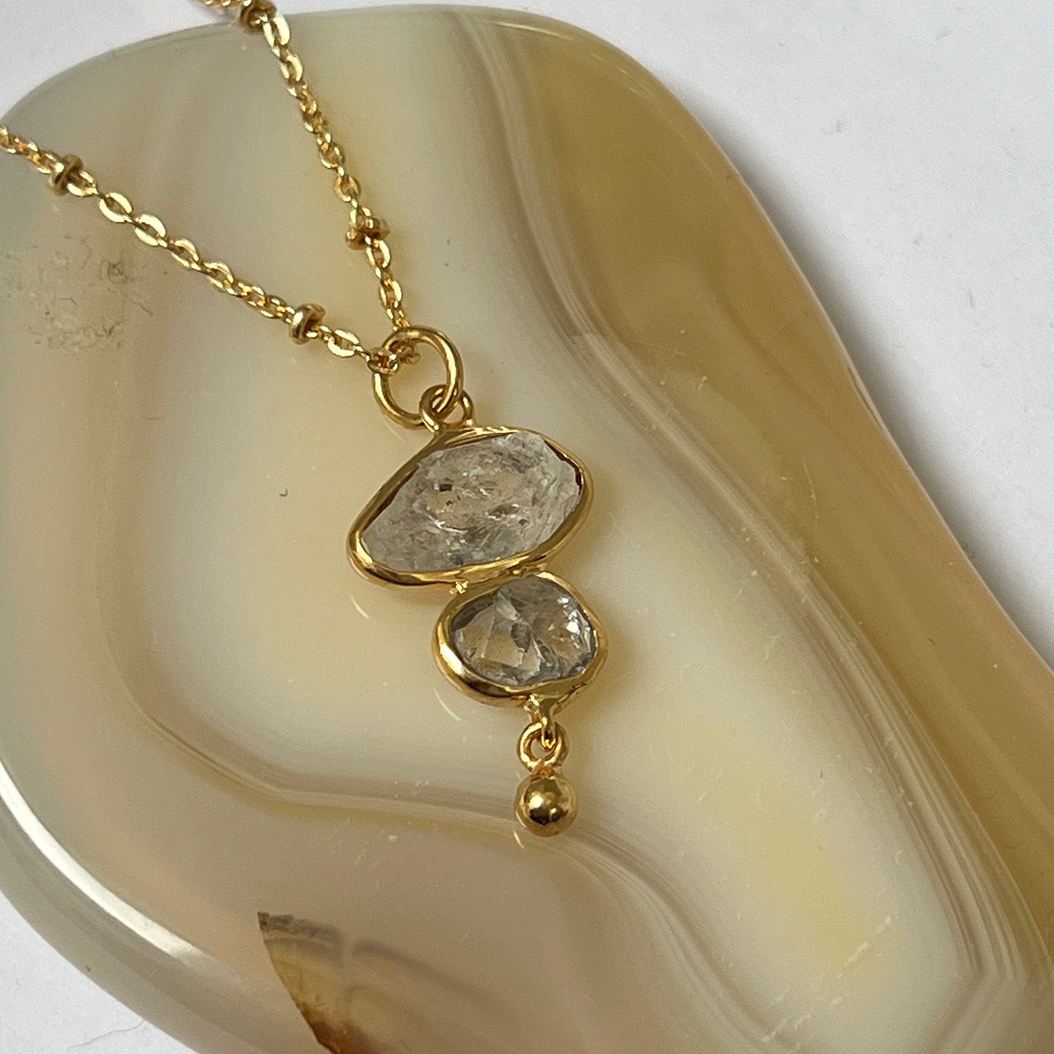 Gold necklace with a pendant on a decorative stone surface