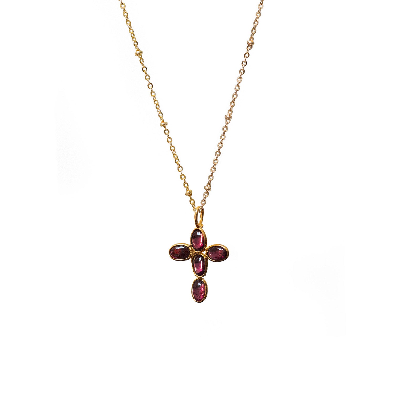 Gold necklace with a cross pendant featuring red garnet gemstones on a white background
