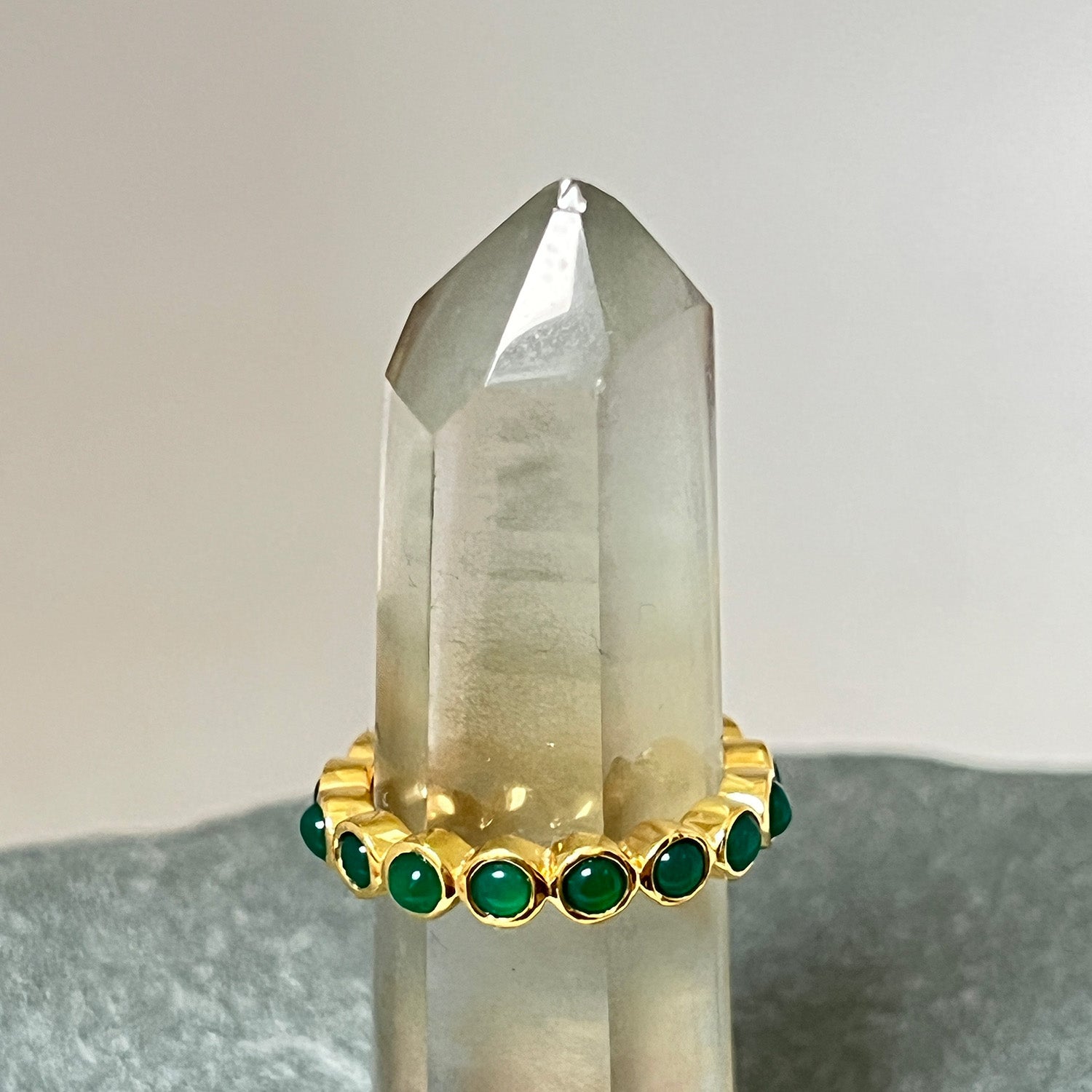 A gold vermeil ring with green onyx cabochons on a background of crystals