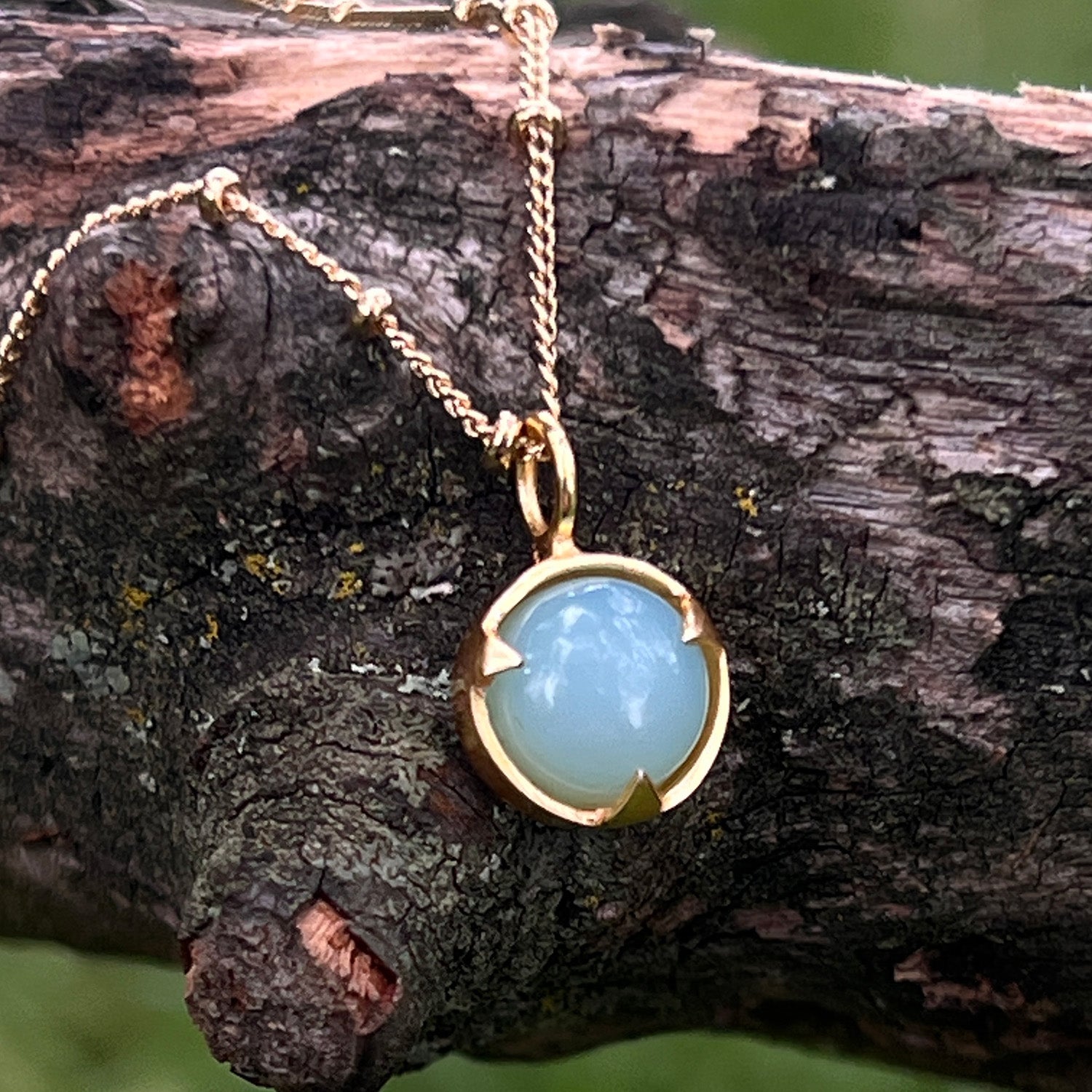 Gold necklace with an aqua chalcedony pendant on a branch
