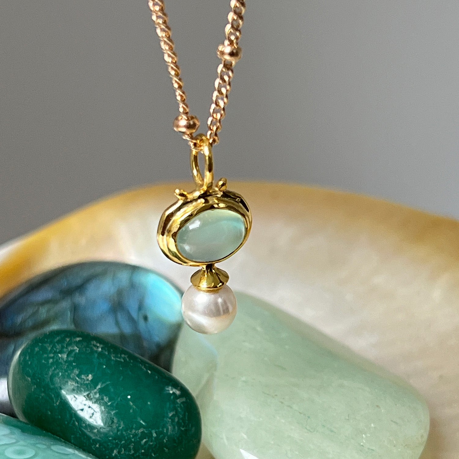 Aqua Chalcedony & Pearl Pendant on a Gold Plated Biba Chain with green crystals in the background
