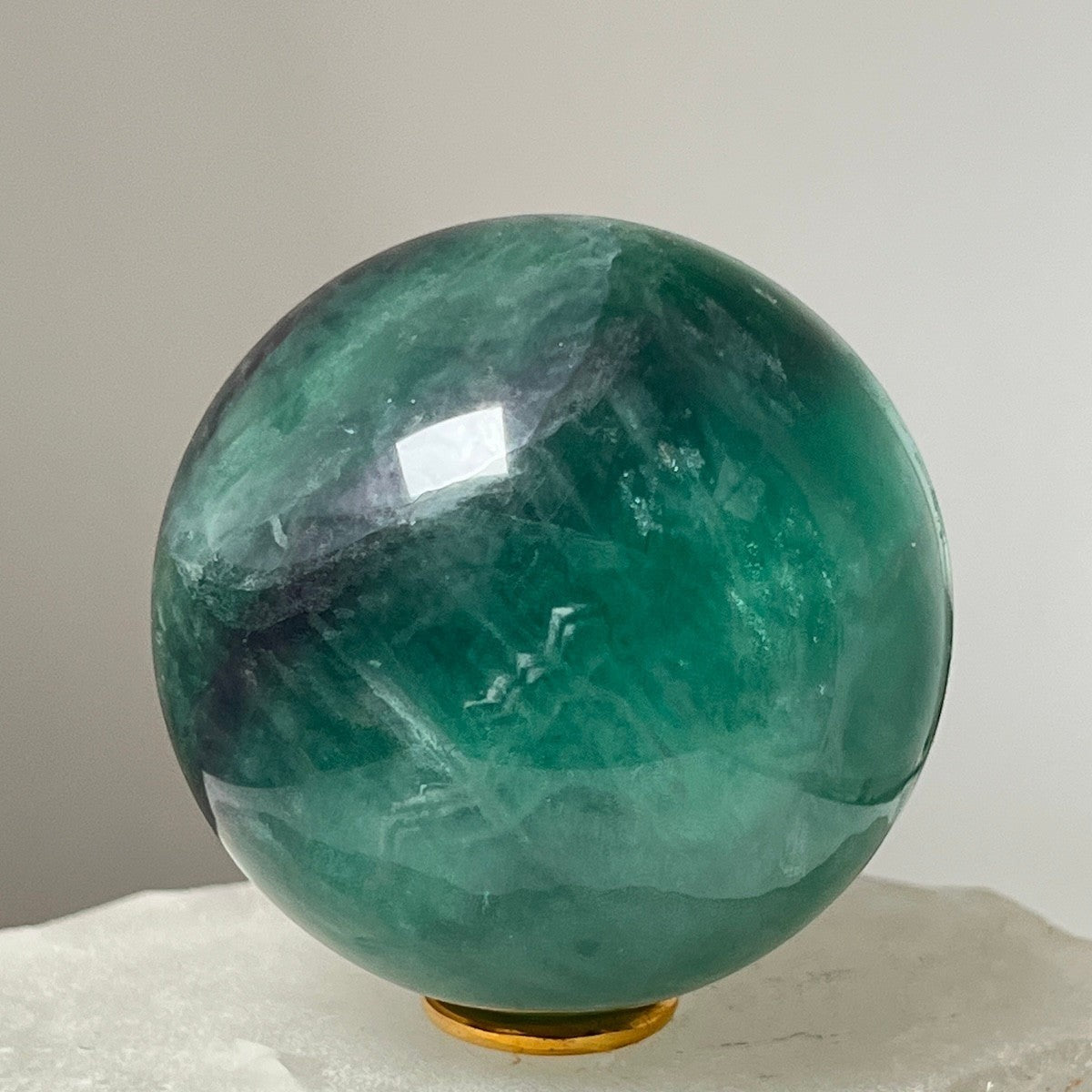 Mirabelle Jewellery polished green fluorite sphere with natural variations in emerald and jade hues, smooth surface.