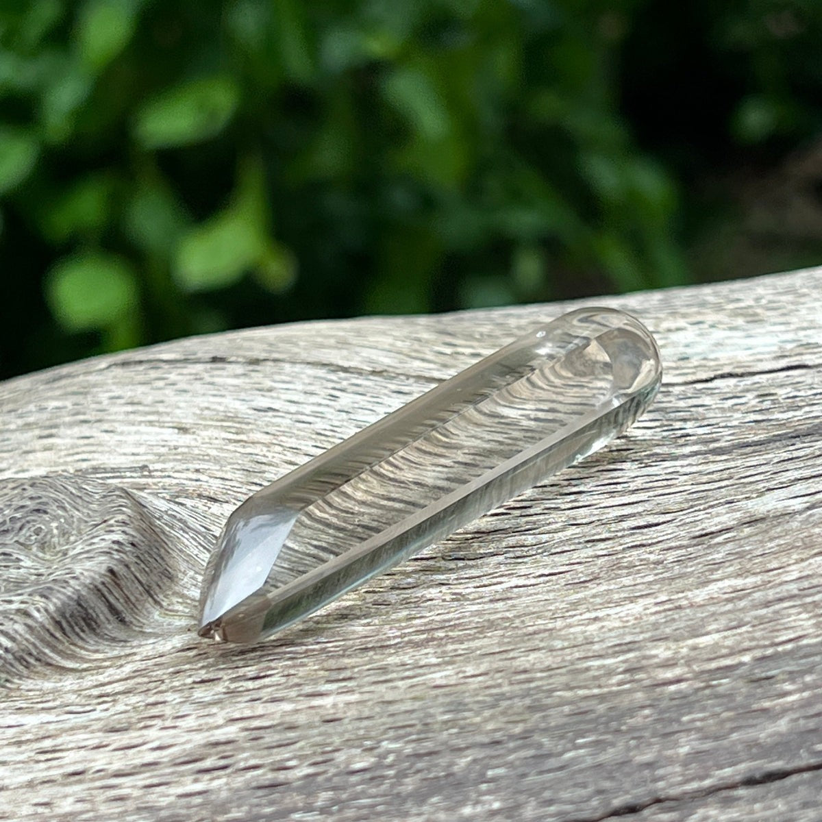 Mirabelle Jewellery light smoky quartz crystal healing wand from Madagascar on a textured wooden surface.