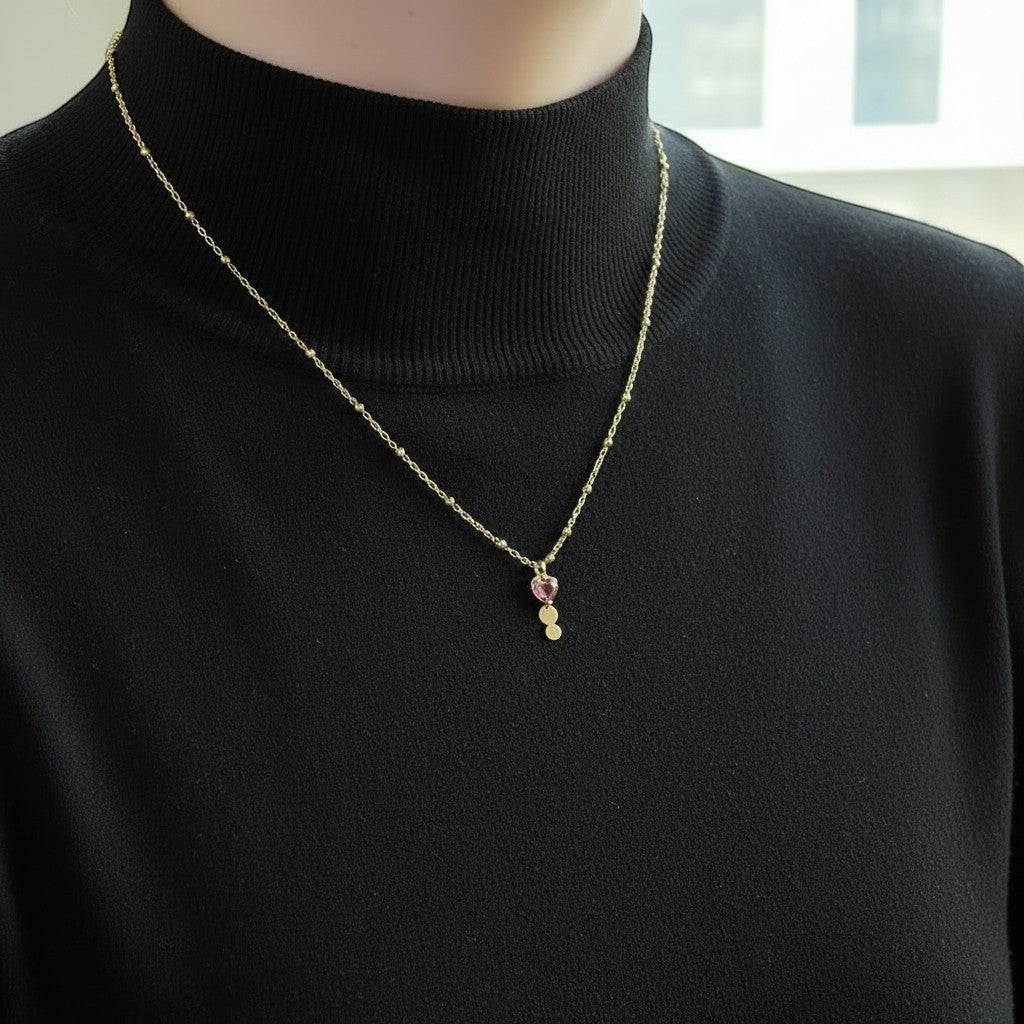 Mirabelle Jewellery gold plated trilogy pendant with a ruby on a delicate satellite chain worn on a black top.
