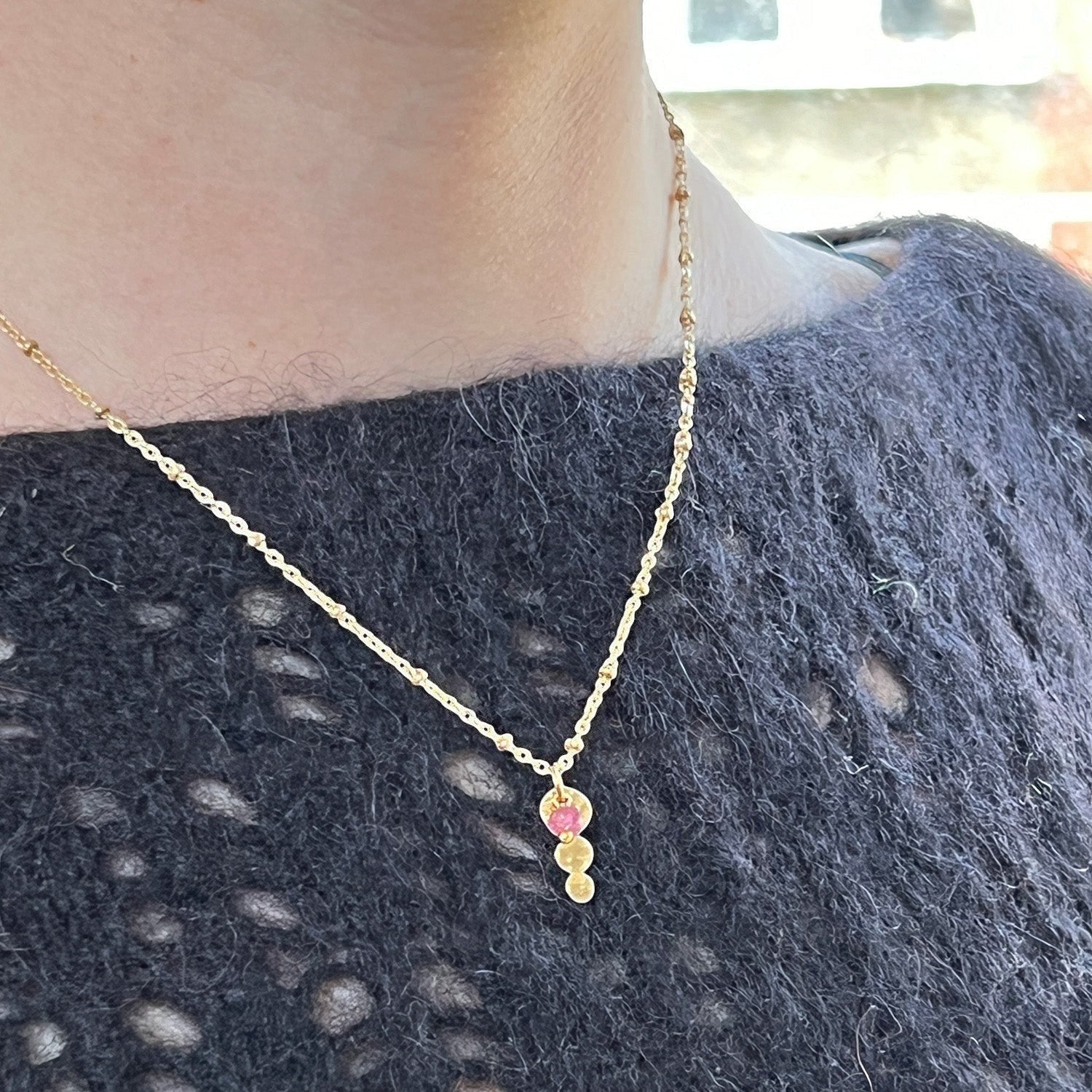 Mirabelle Jewellery gold plated Trilogy pendant with a Burmese ruby on a delicate satellite chain worn on a neck.