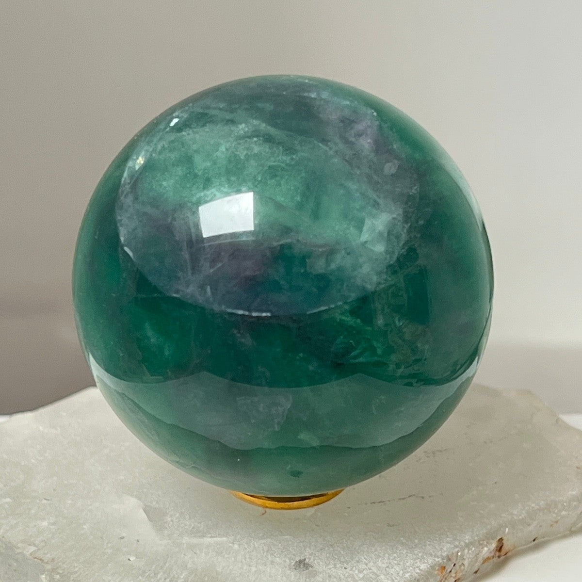 Mirabelle Jewellery polished green fluorite sphere with purple inclusions, smooth and cool to touch, ideal for meditation and decor.