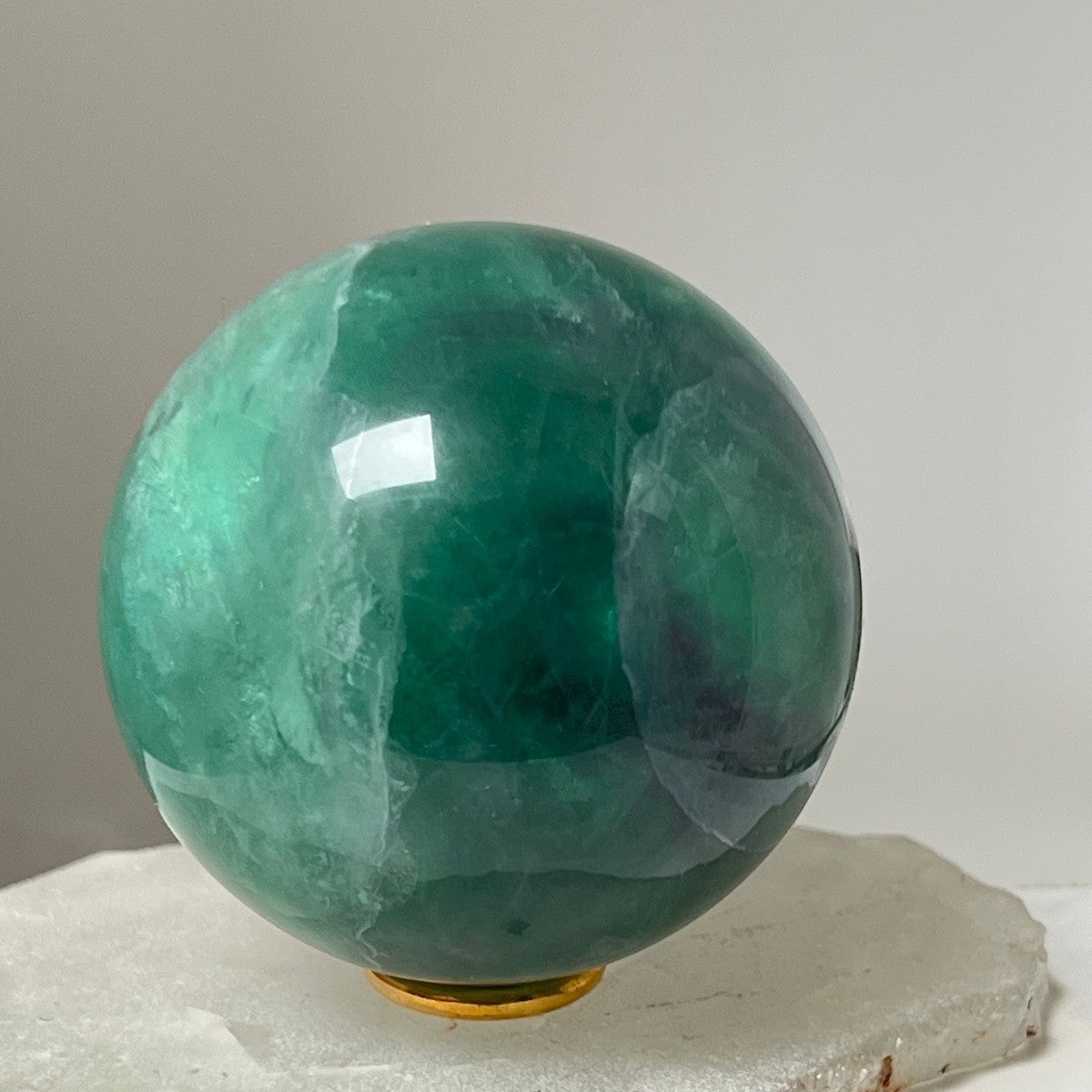 Mirabelle Jewellery polished green fluorite sphere with natural variations in emerald and jade hues, smooth surface.