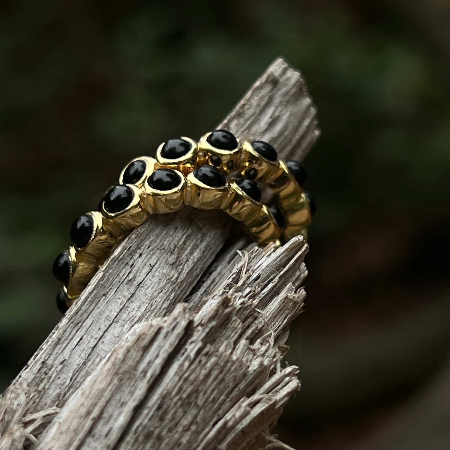 Gold ring with black onyx stones on a wooden surface
