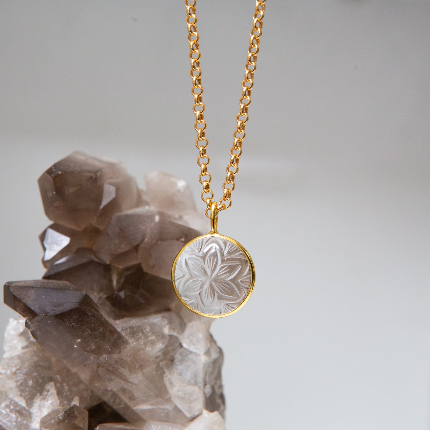 Gold necklace with a floral pendant on a crystal background