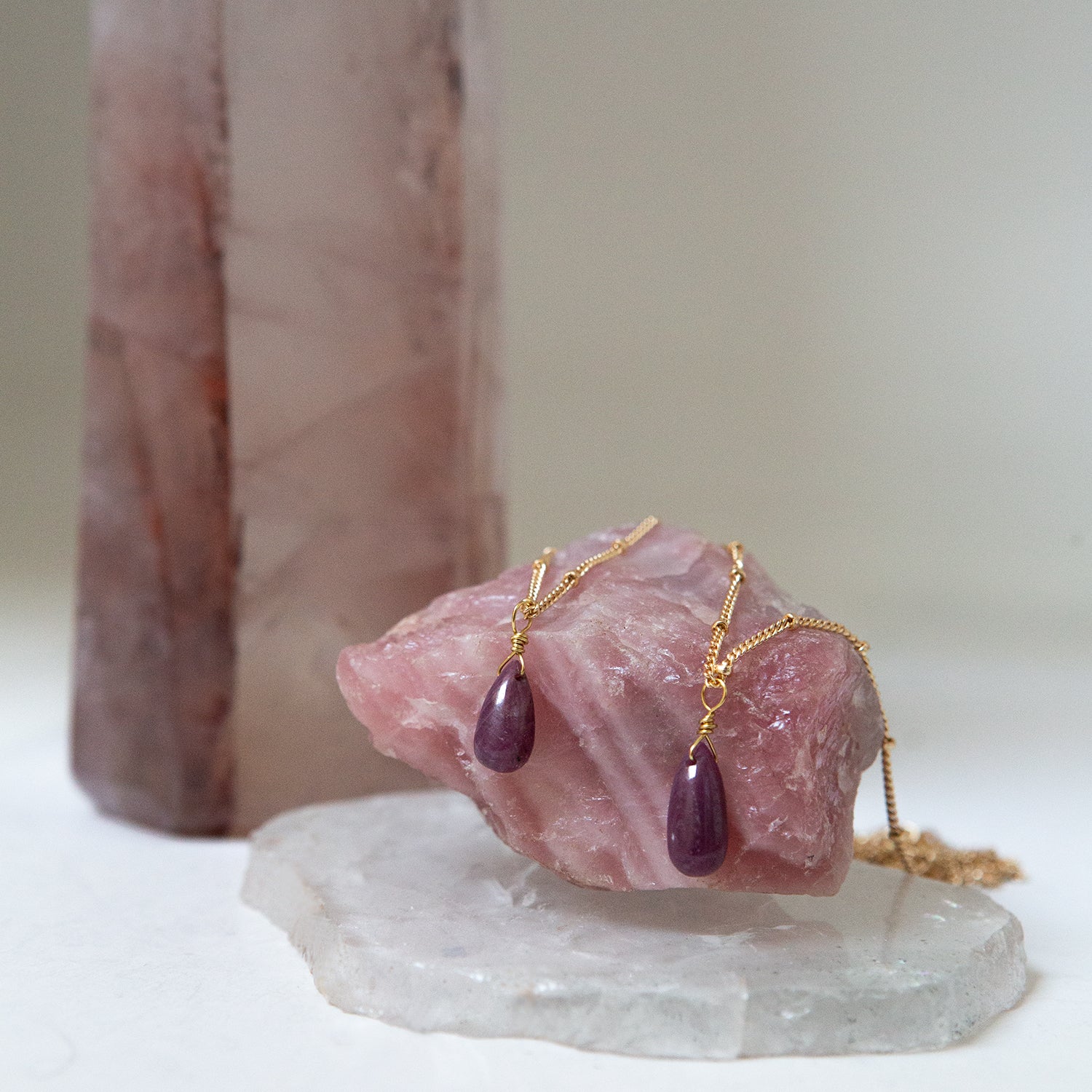Gold necklace with ruby pendant on a pink crystal