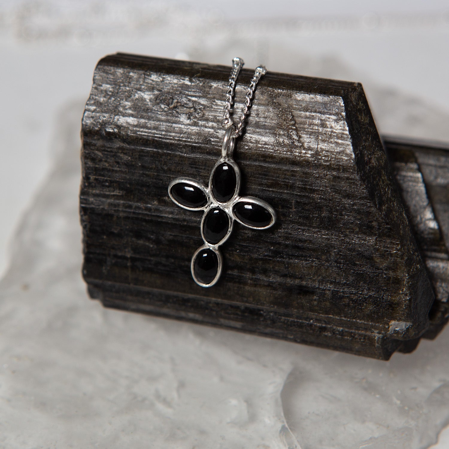 Silver necklace with black onyx pendant on a wooden block
