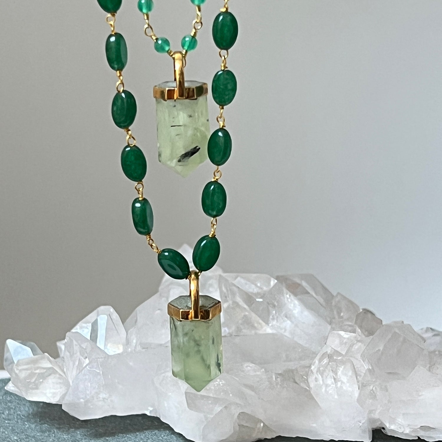 Necklace with green onyx and a gold pendant on a white crystal base