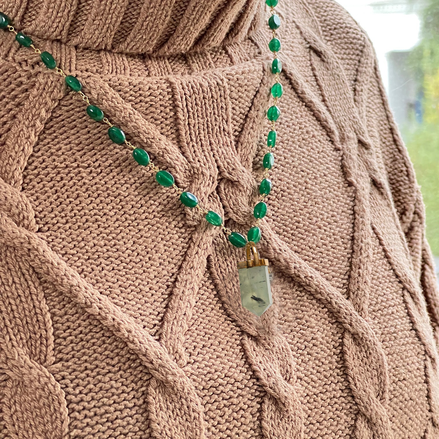 Green onyx necklace on a brown knitted jumper
