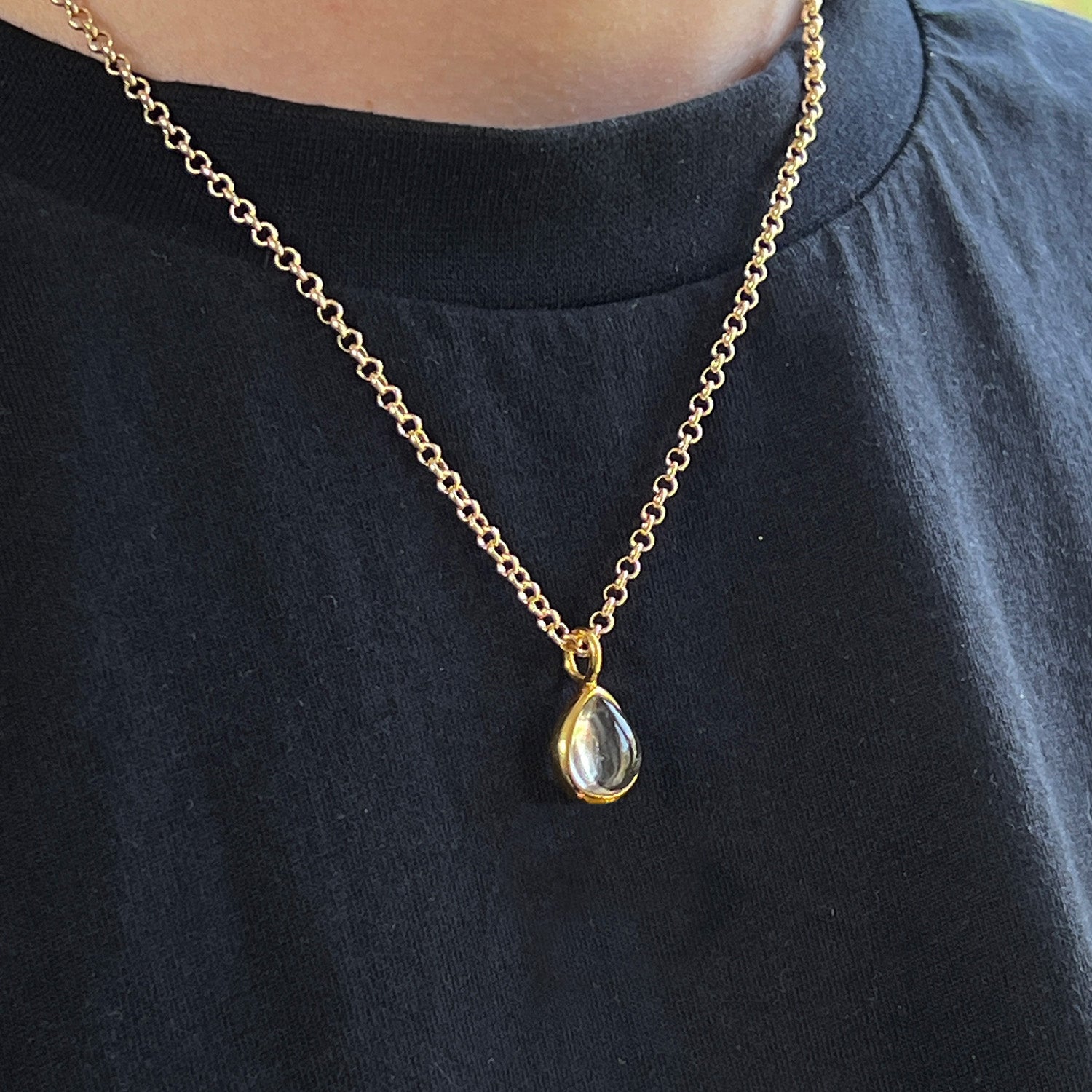 Gold necklace with a teardrop rock crystal pendant on a black shirt