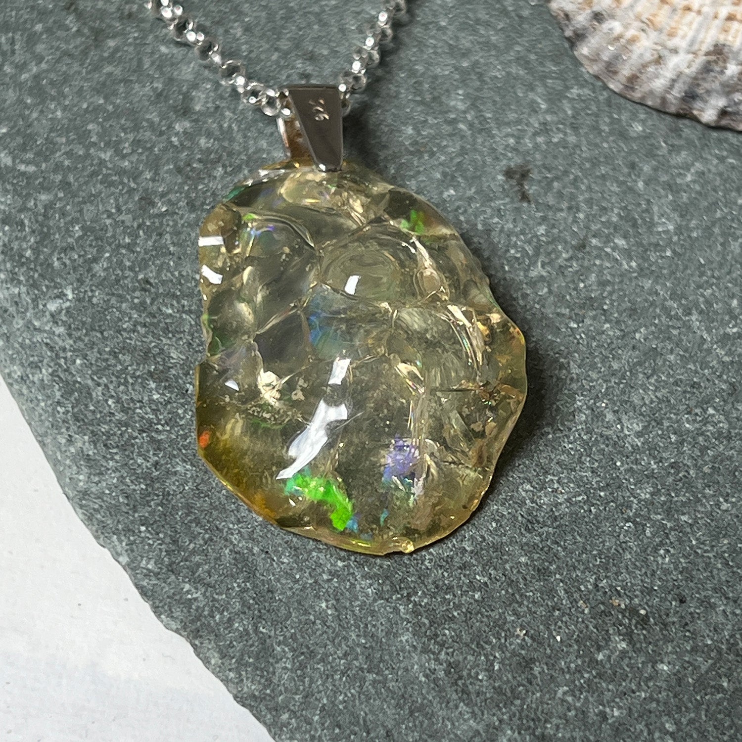 Necklace with a textured unique Ethiopian fire opal pendant on a grey background
