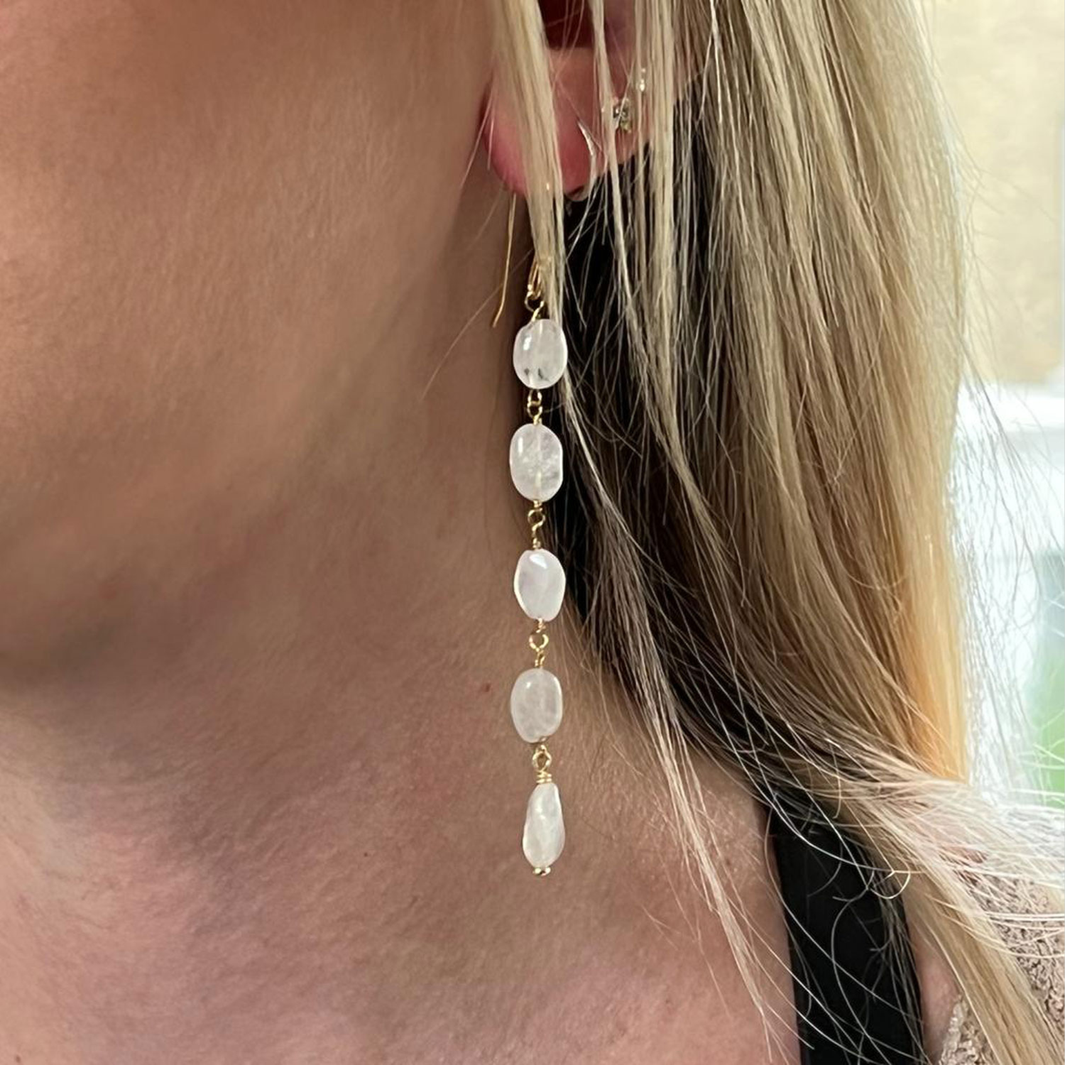 A close-up of a model's ear wearing a five stone moonstone earring.