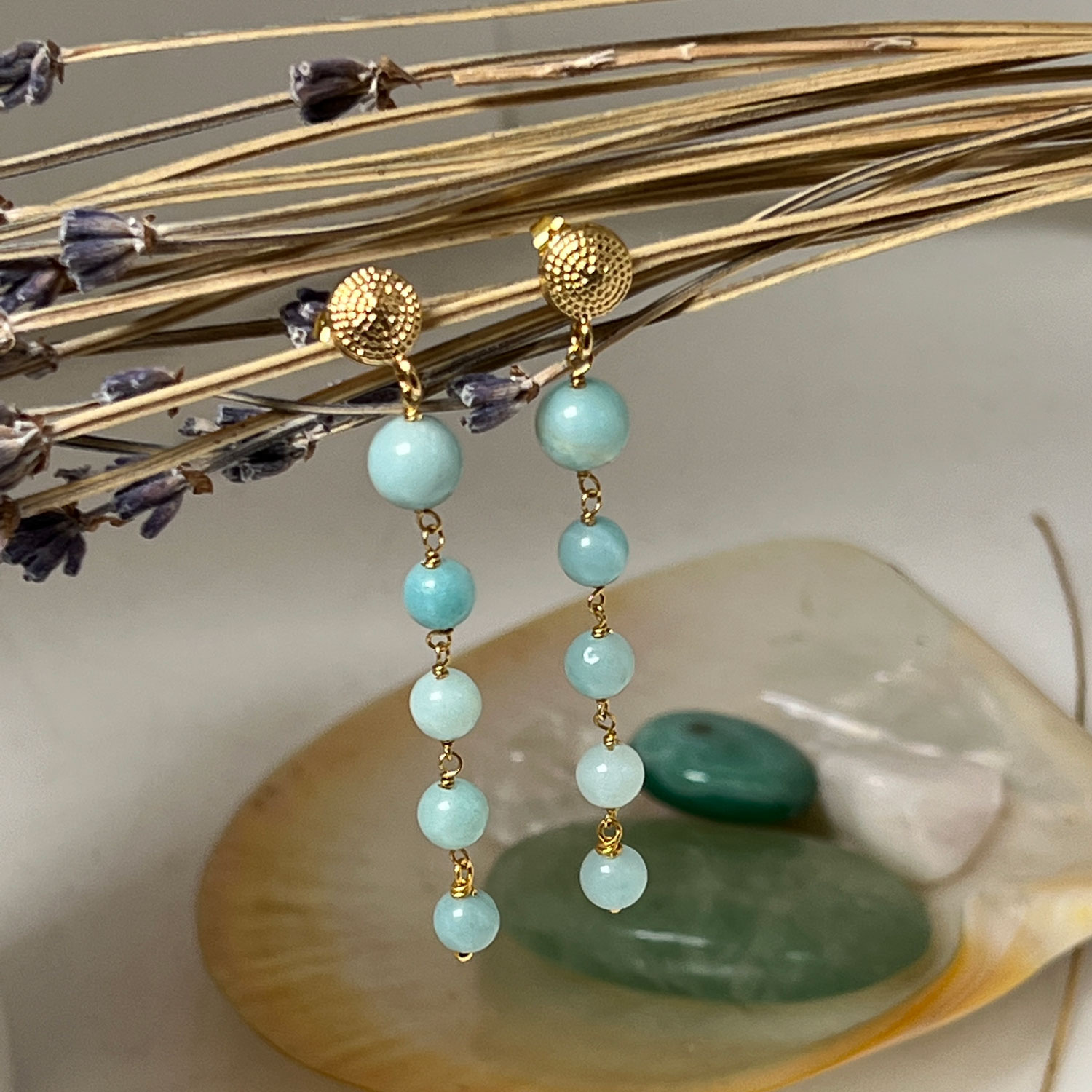 Amazonite 5 Stone Amazonite Earrings |hanging from some dried flowers. There are crsytals in the background.