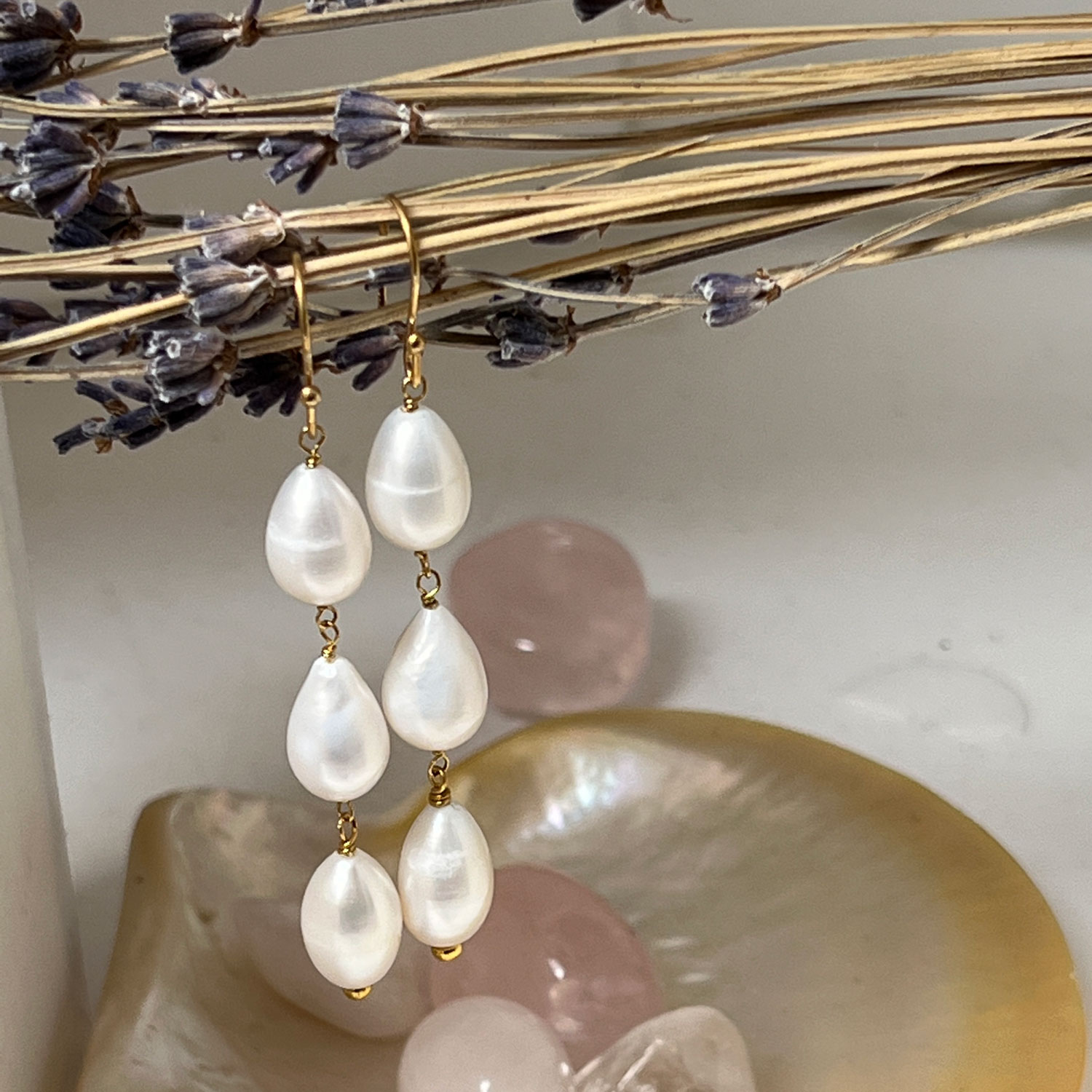 A pair of gold-plated sterling silver earrings featuring three drop-shaped freshwater pearls hanging from some dired flowers