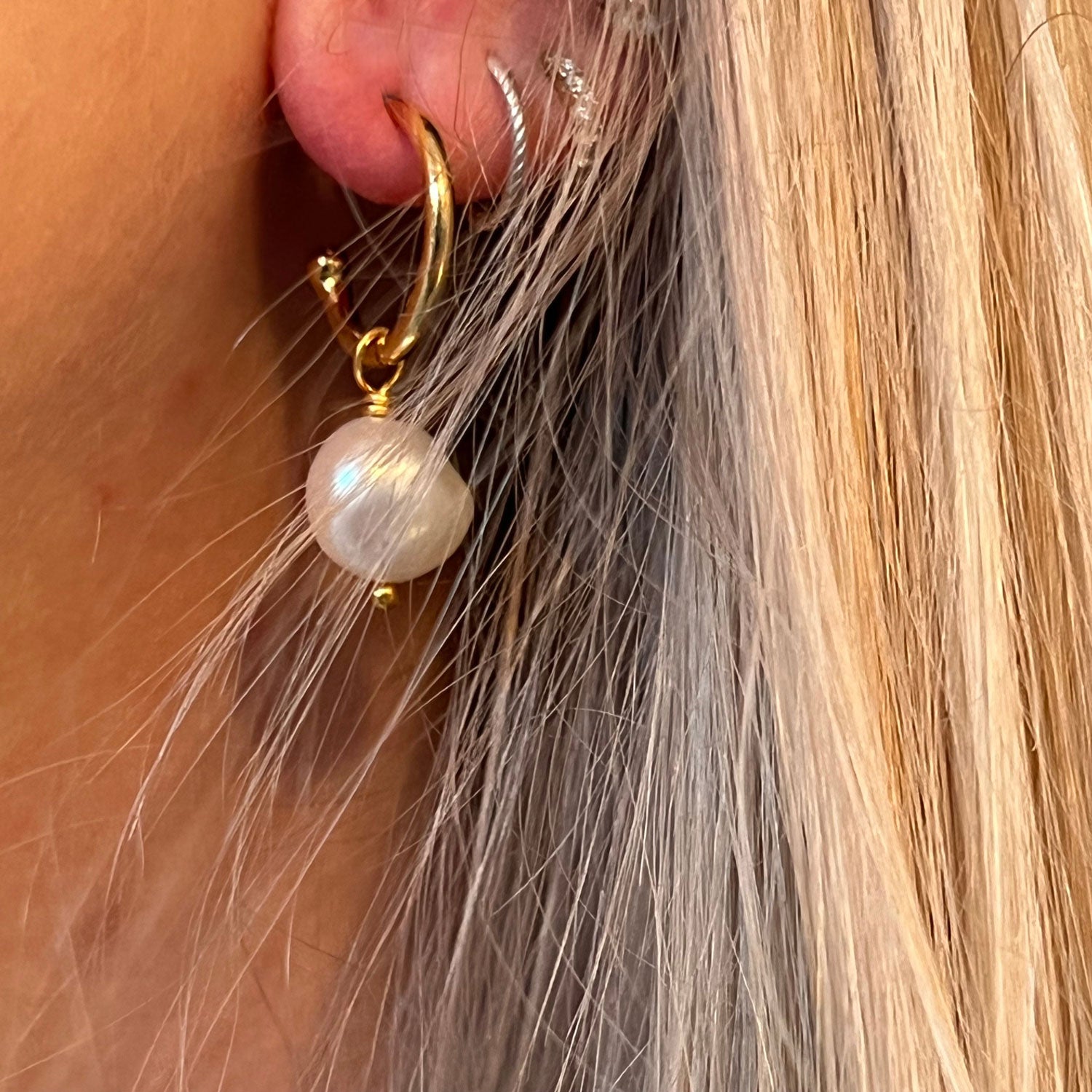 Close up of a model's ear wearing a gold creole freshwater pearl earring
