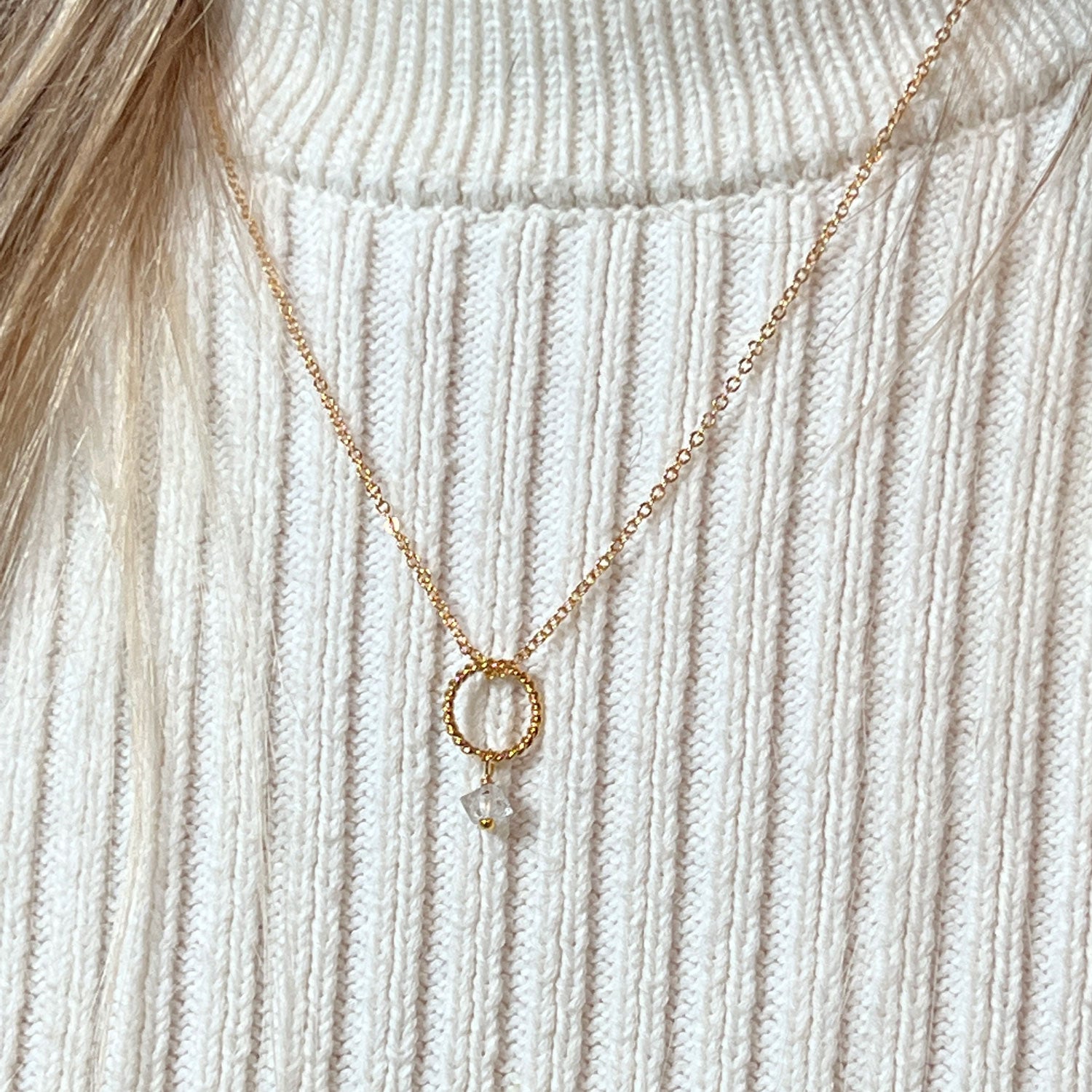 Herkimer quartz diamond pendant on a gold-plated chain worn against a cream jumper