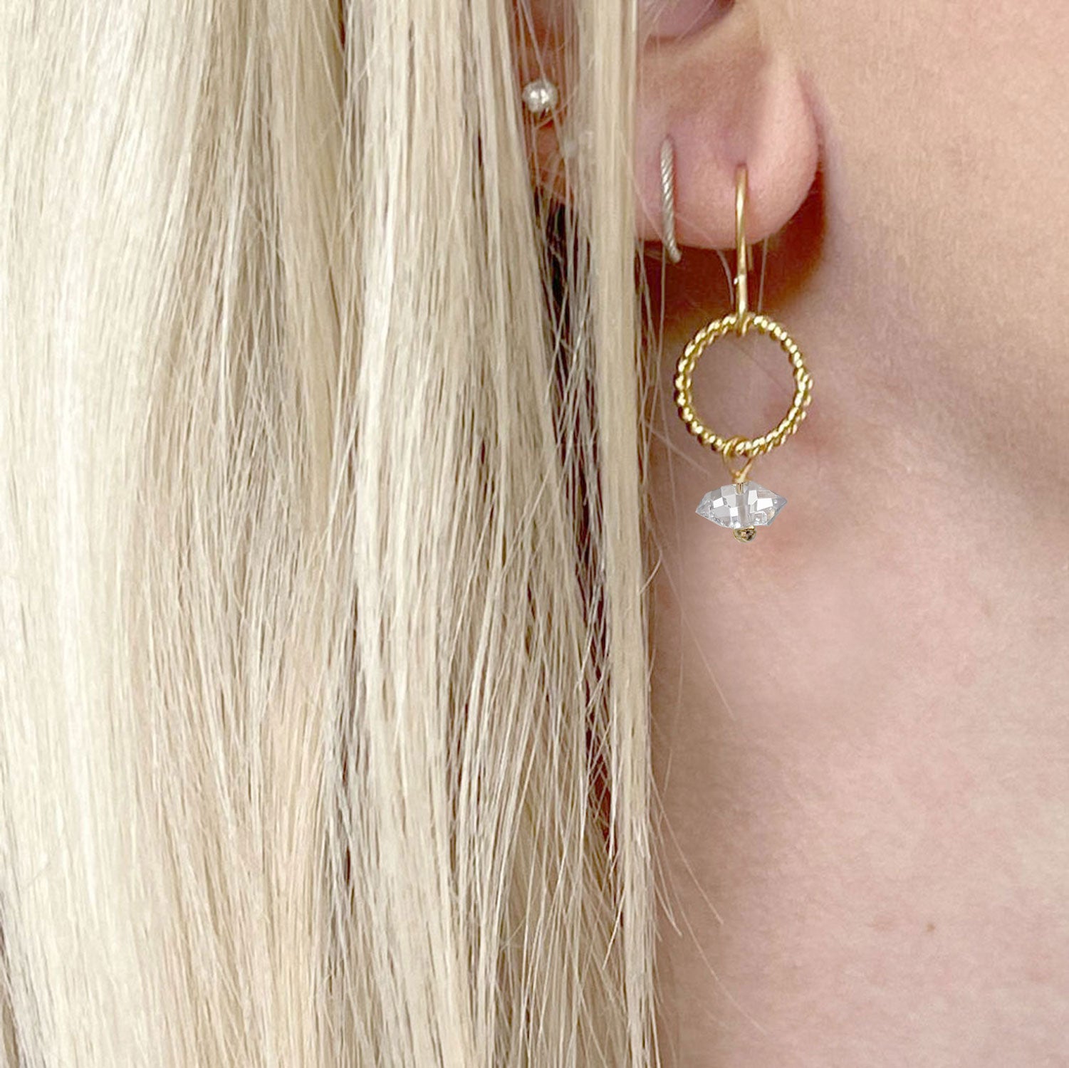 Herkimer quartz diamond earring in a gold-plated loop worn in a model's ear