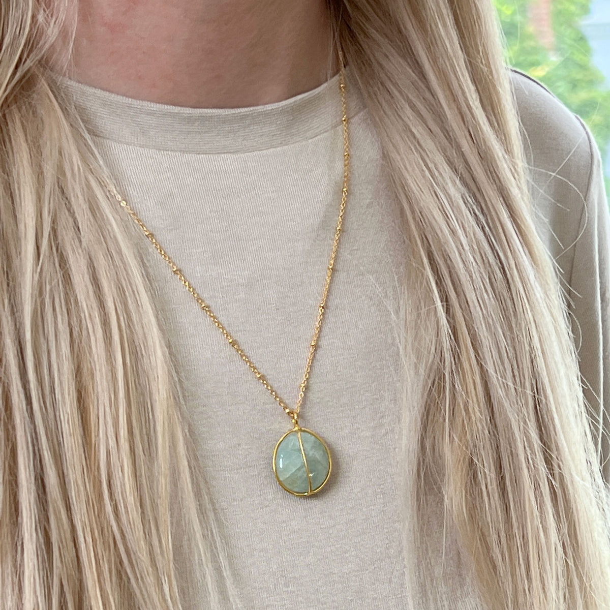 Gold plated aquamarine necklace worn against a cream sweater
